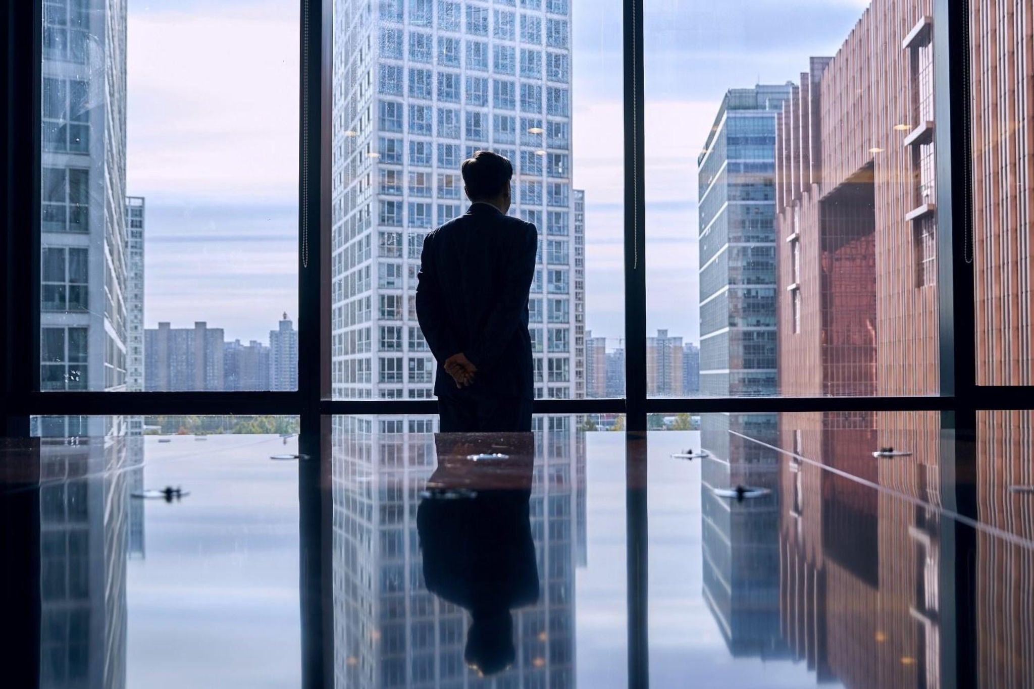 Back view of a man staring outside the window in a high rise building