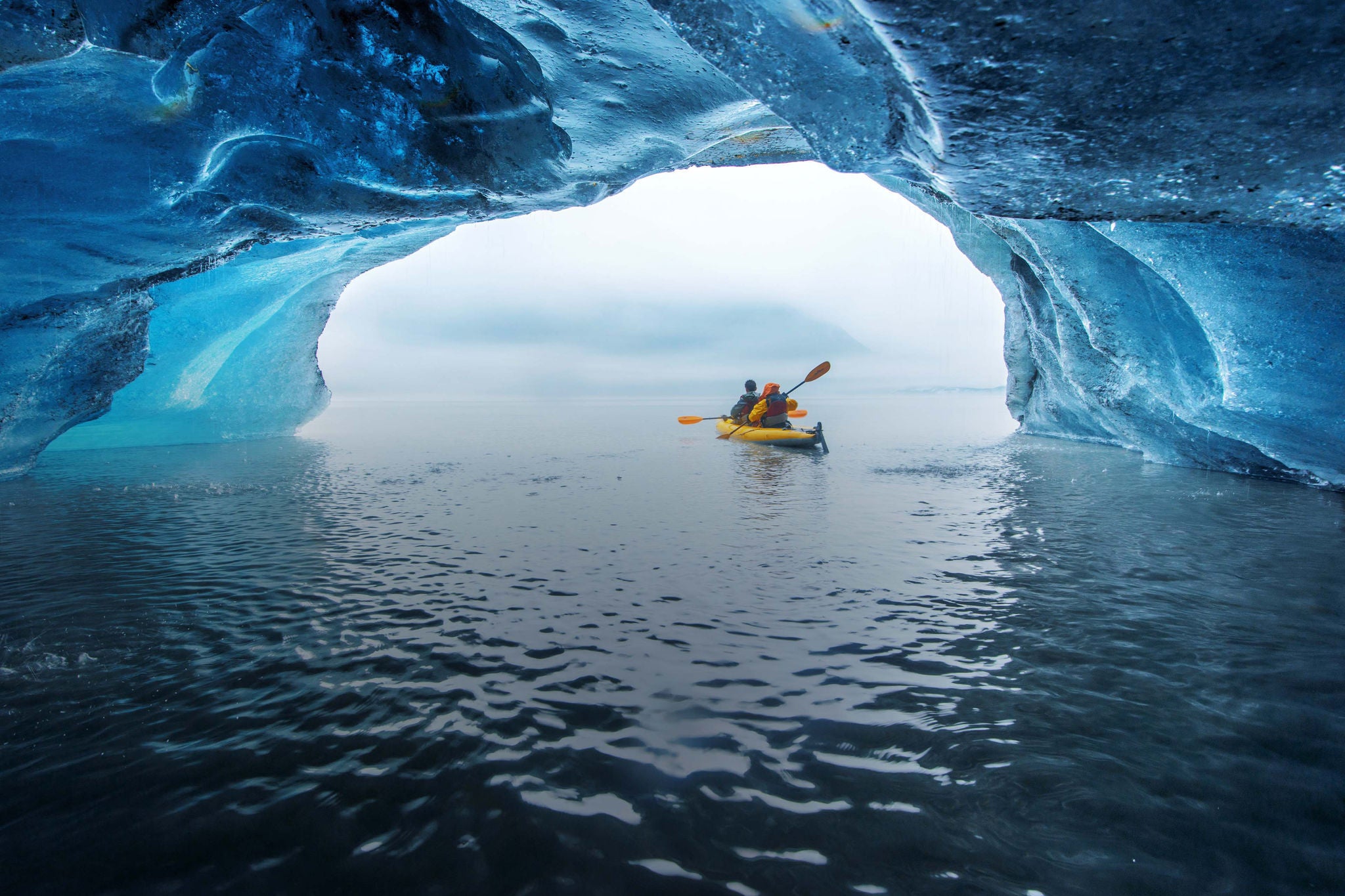 Travellers kayak in blue ice cave at Valdez Glacier.