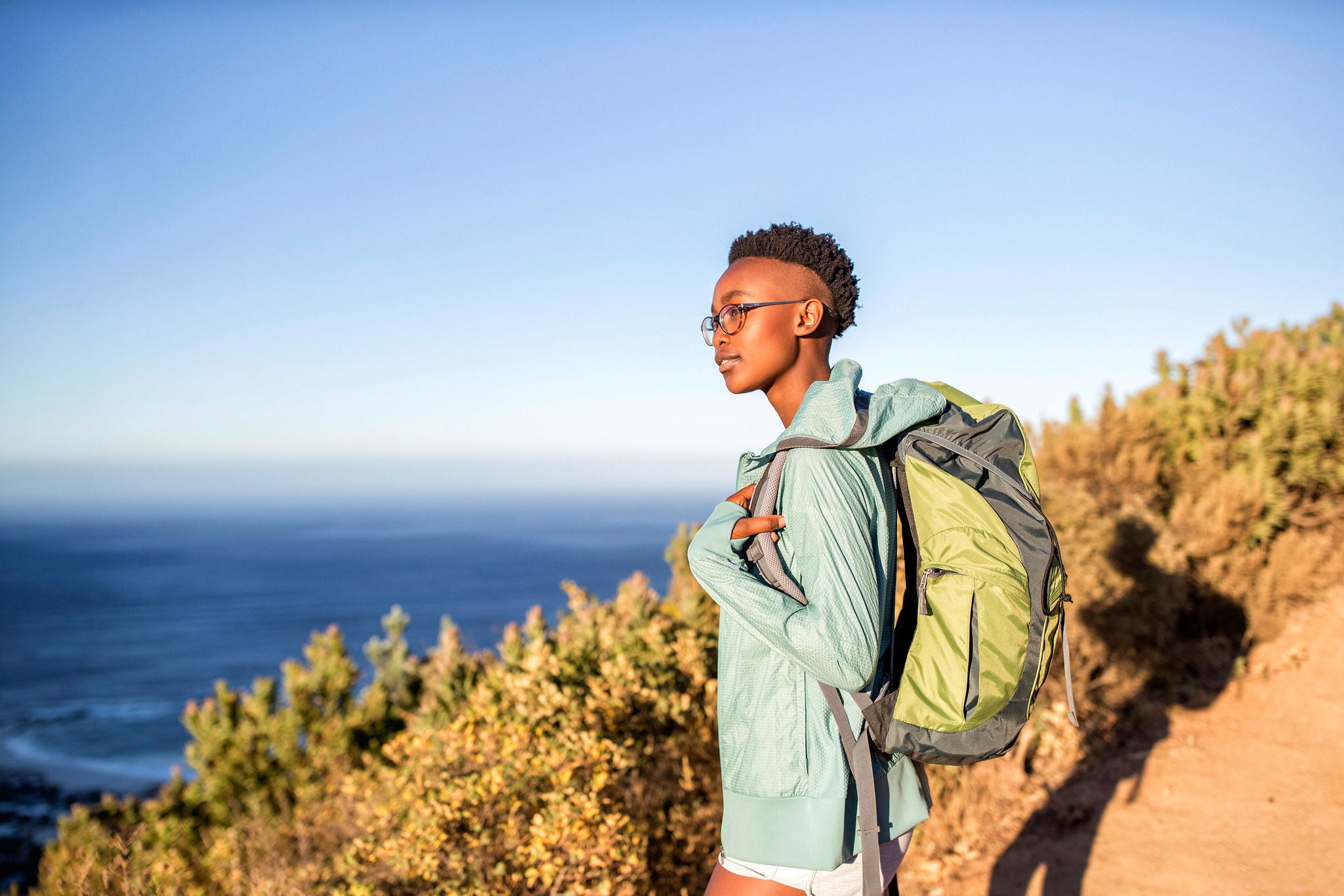EY Young woman on a hiking trip at the coast looking at view
