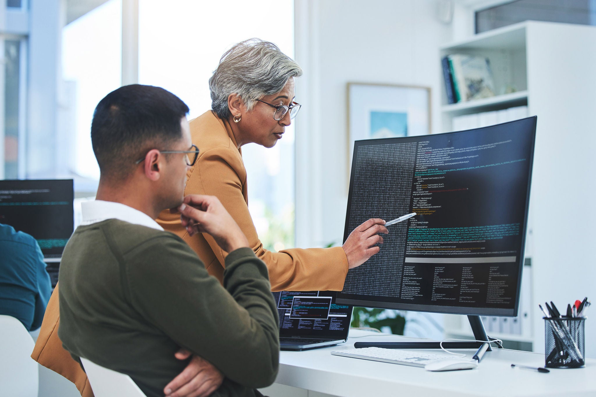 Two people reviewing code together on a large screen