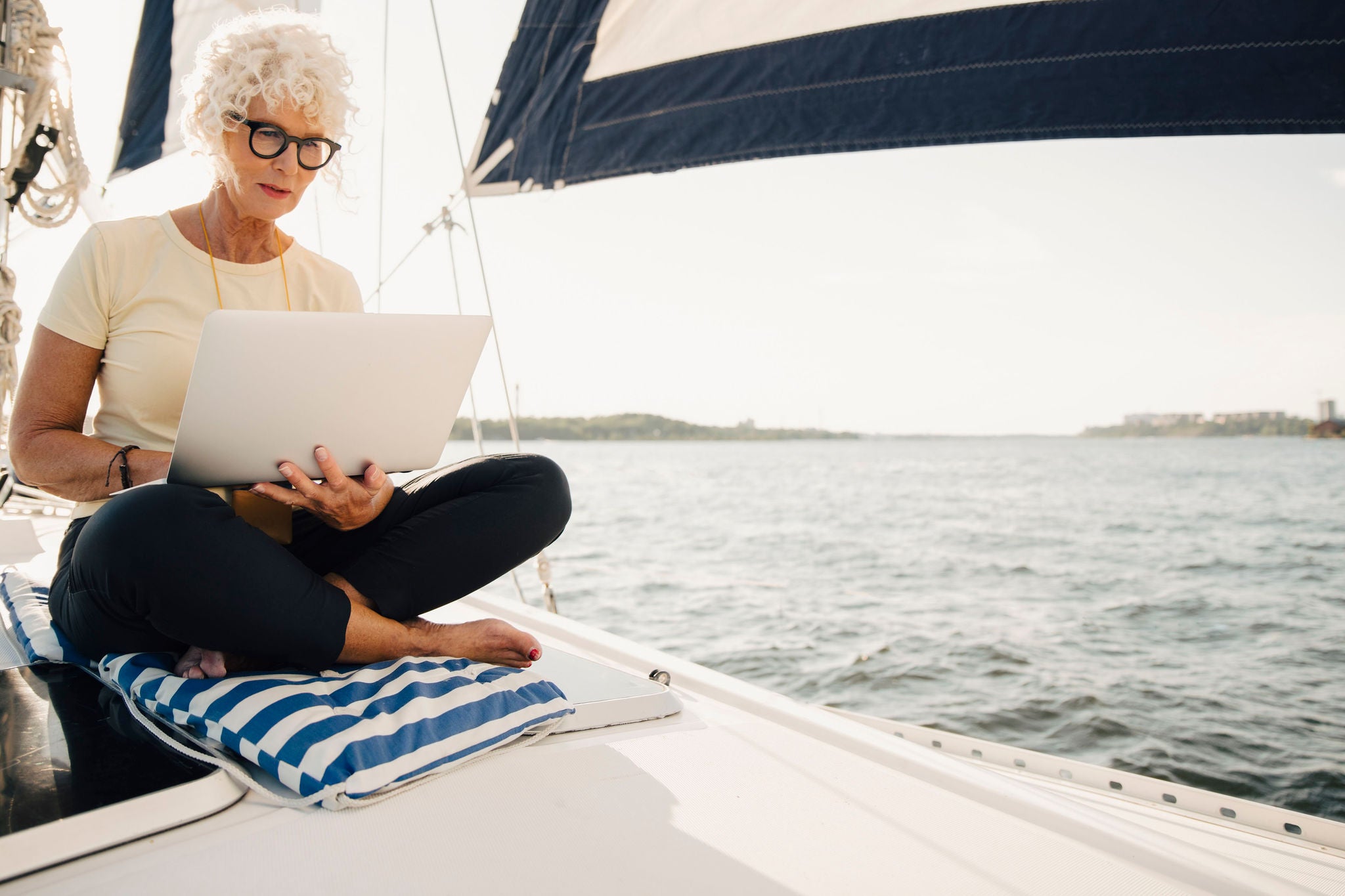 Senior woman working remotely while sailing boat on sunny day