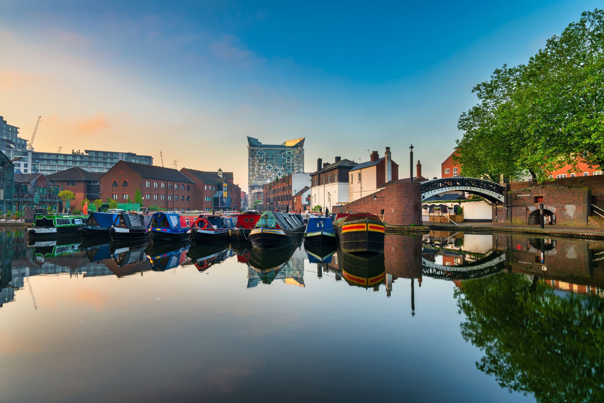 Colourful canal boats lined along a calm city canal