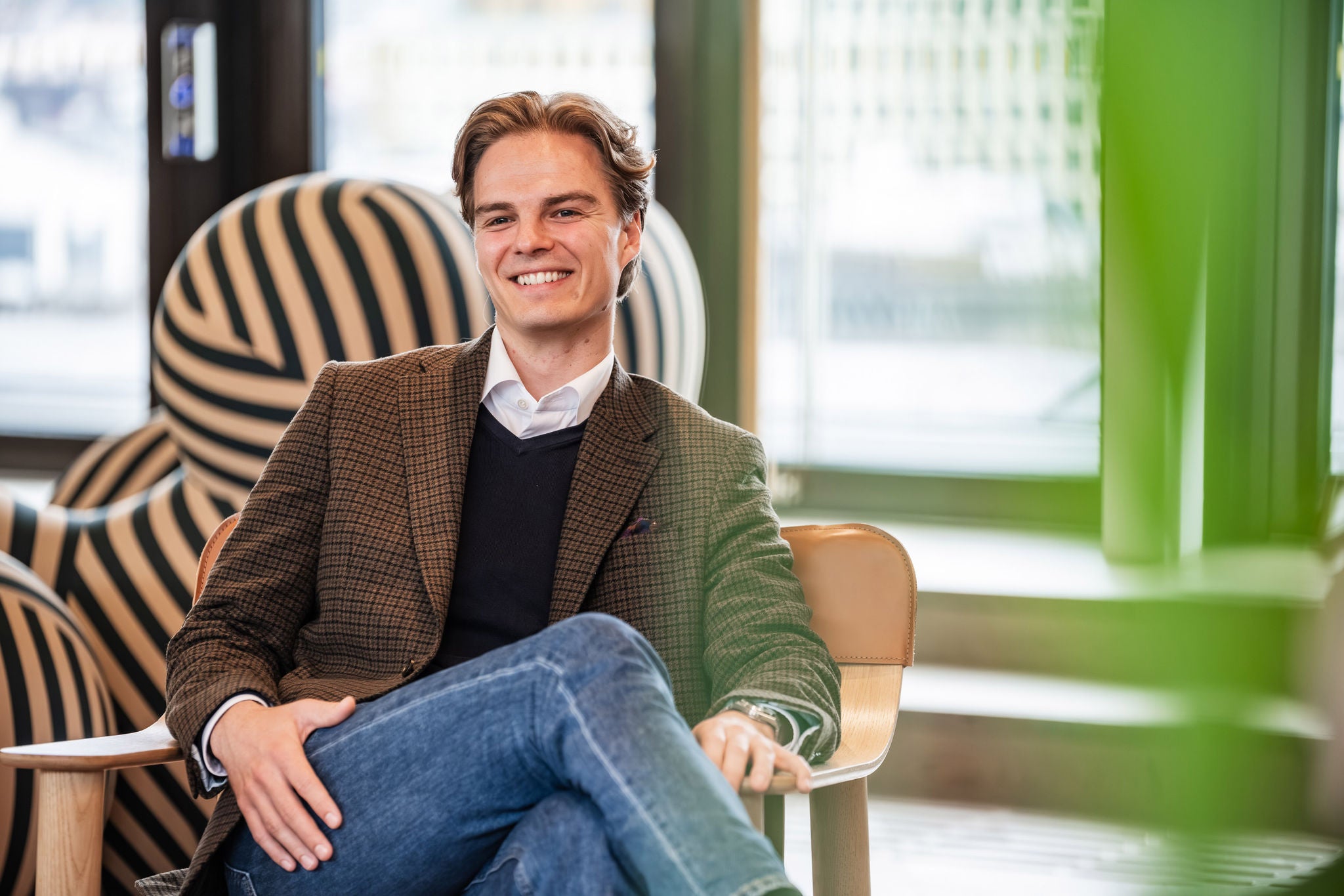 Professional seated in a lounge chair at the EY Norway office, with large windows and modern office furnishings in the background.