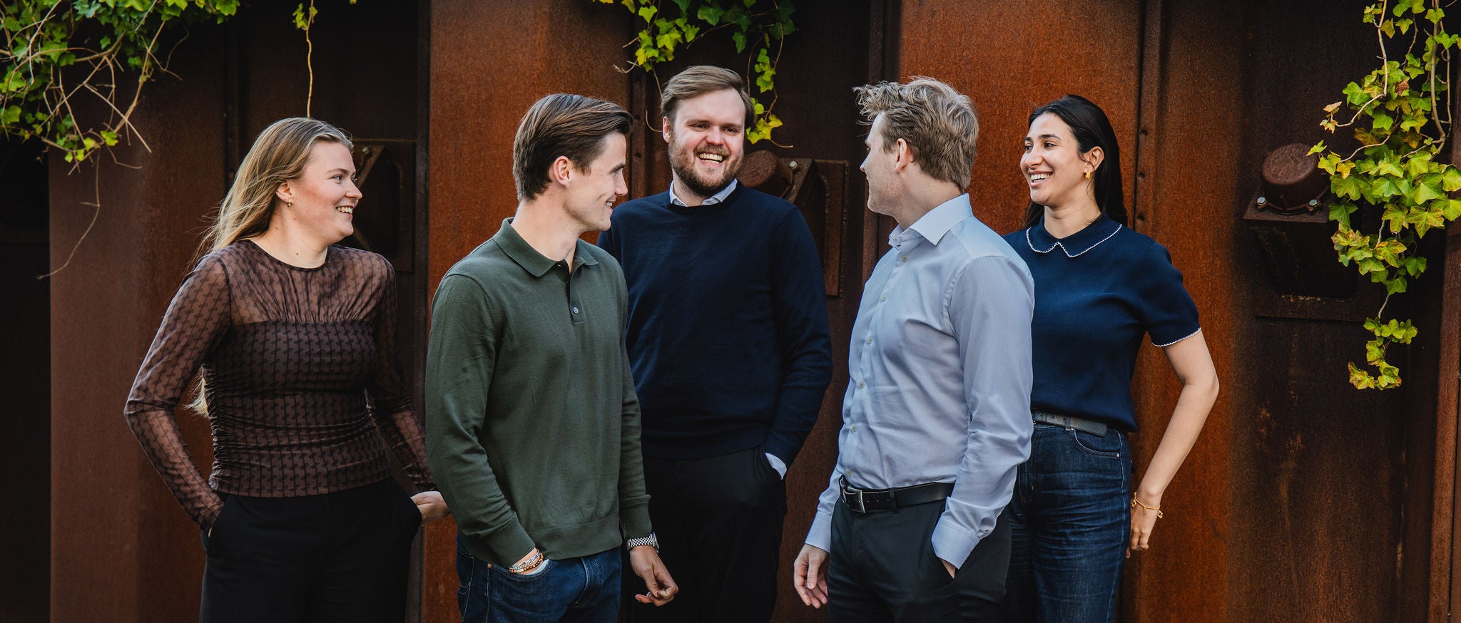 Five young employees standing outside talking