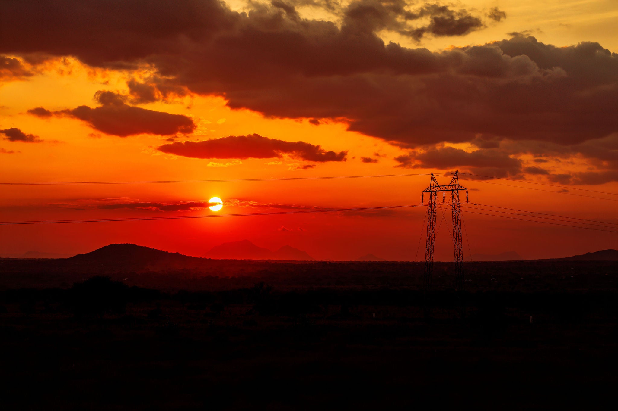 Silhouette of electricity pylon against sunset sky