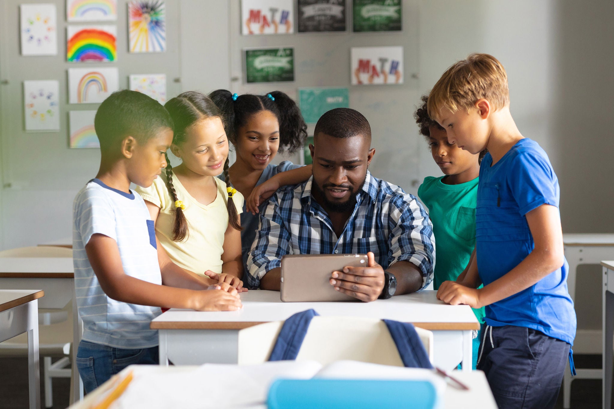 African american young male teacher showing digital tablet to multiracial elementary students, African american young male teacher showing digital tablet to mu