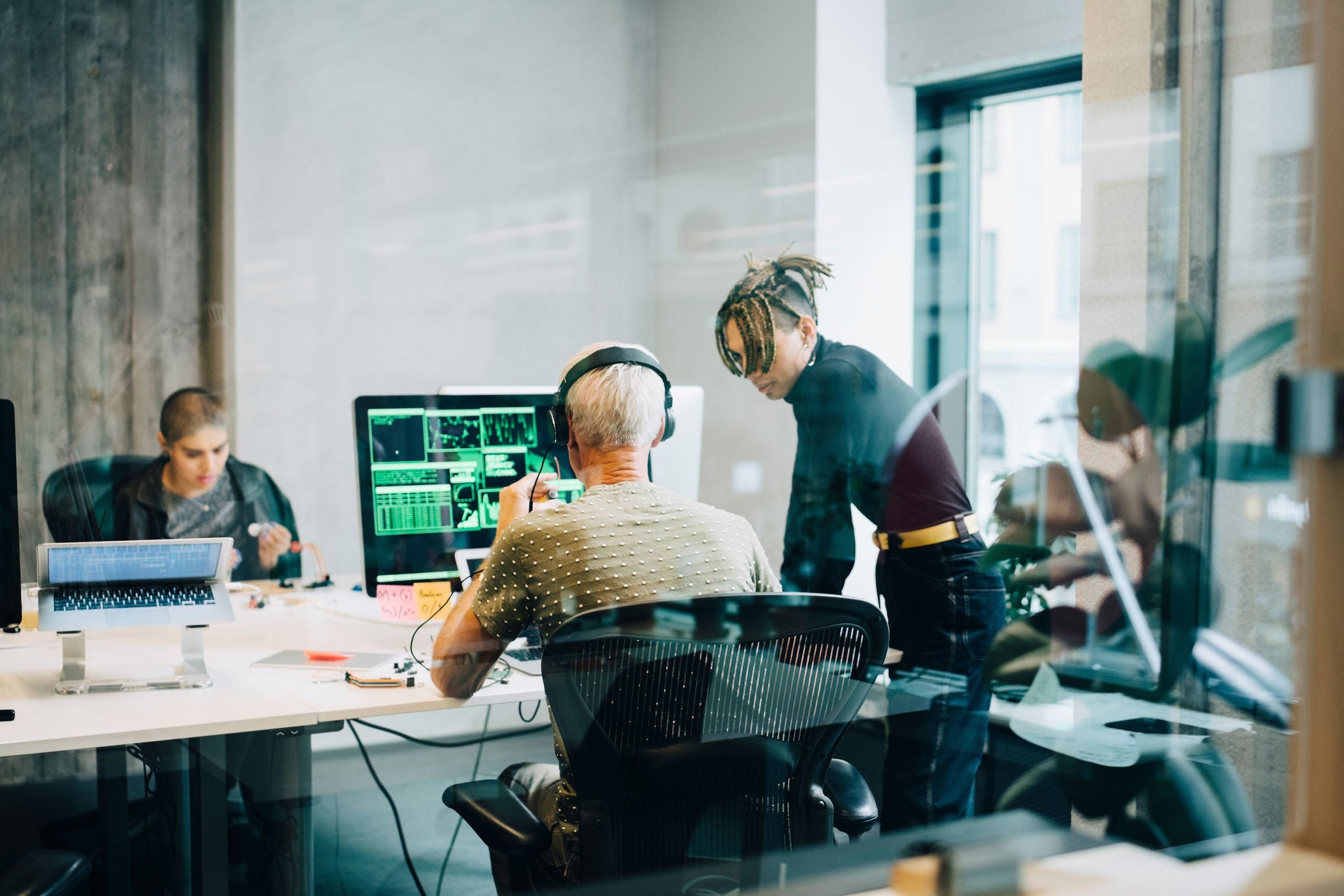 Équipe collaborant dans un bureau moderne avec ordinateurs et écrans de design