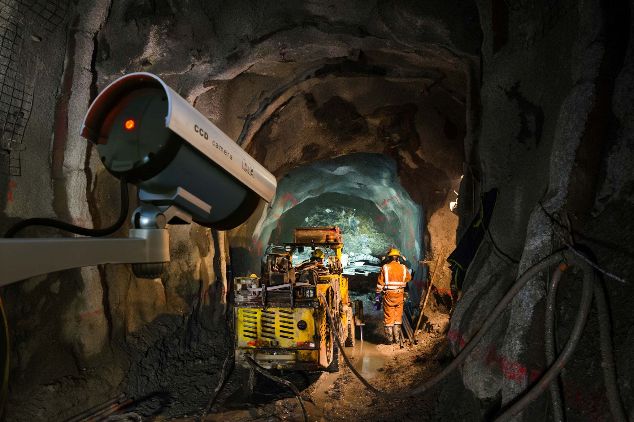 Security camera monitoring underground mining operations with equipment inside a tunnel.