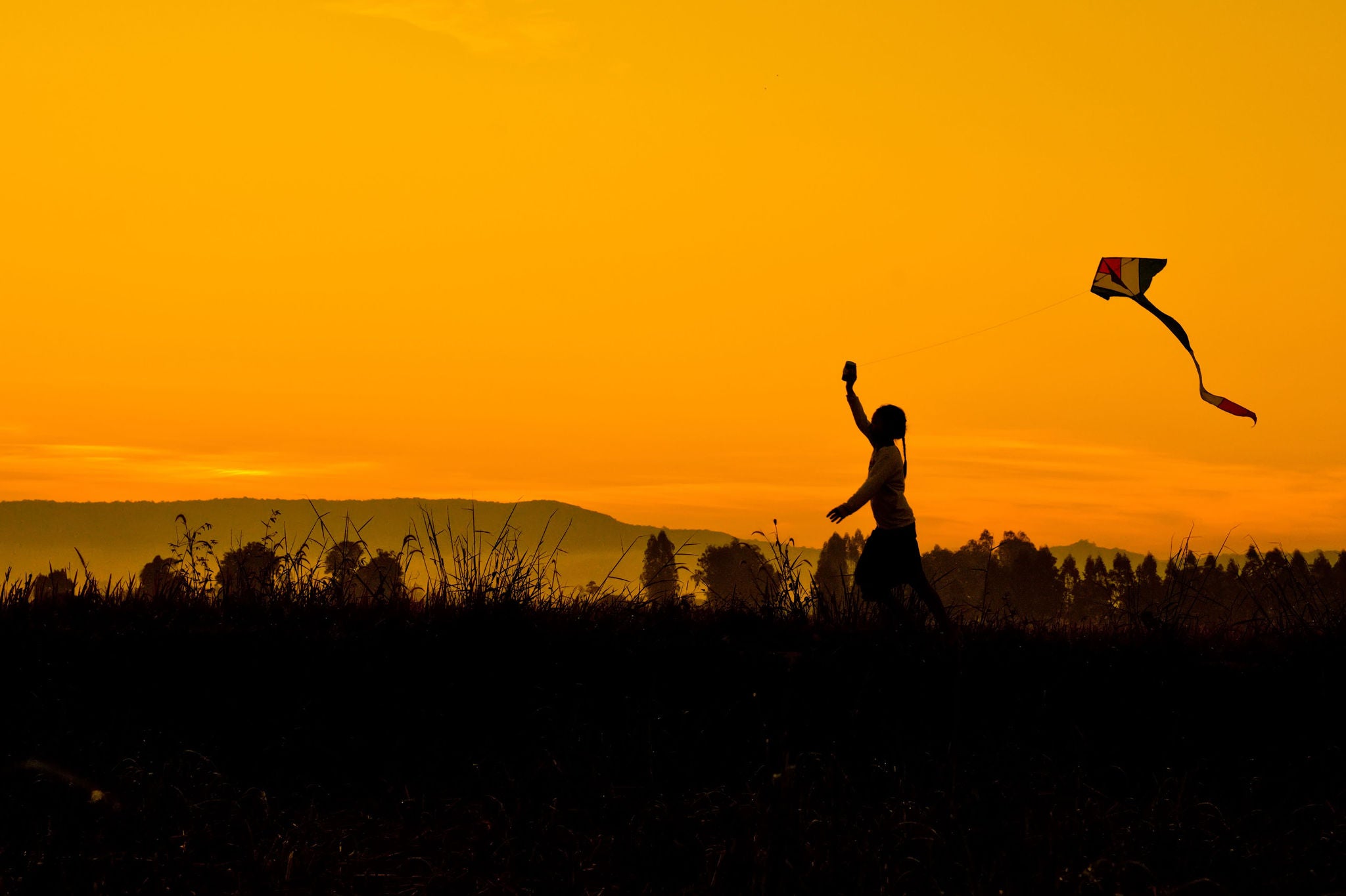 Girl running with kite at sunset