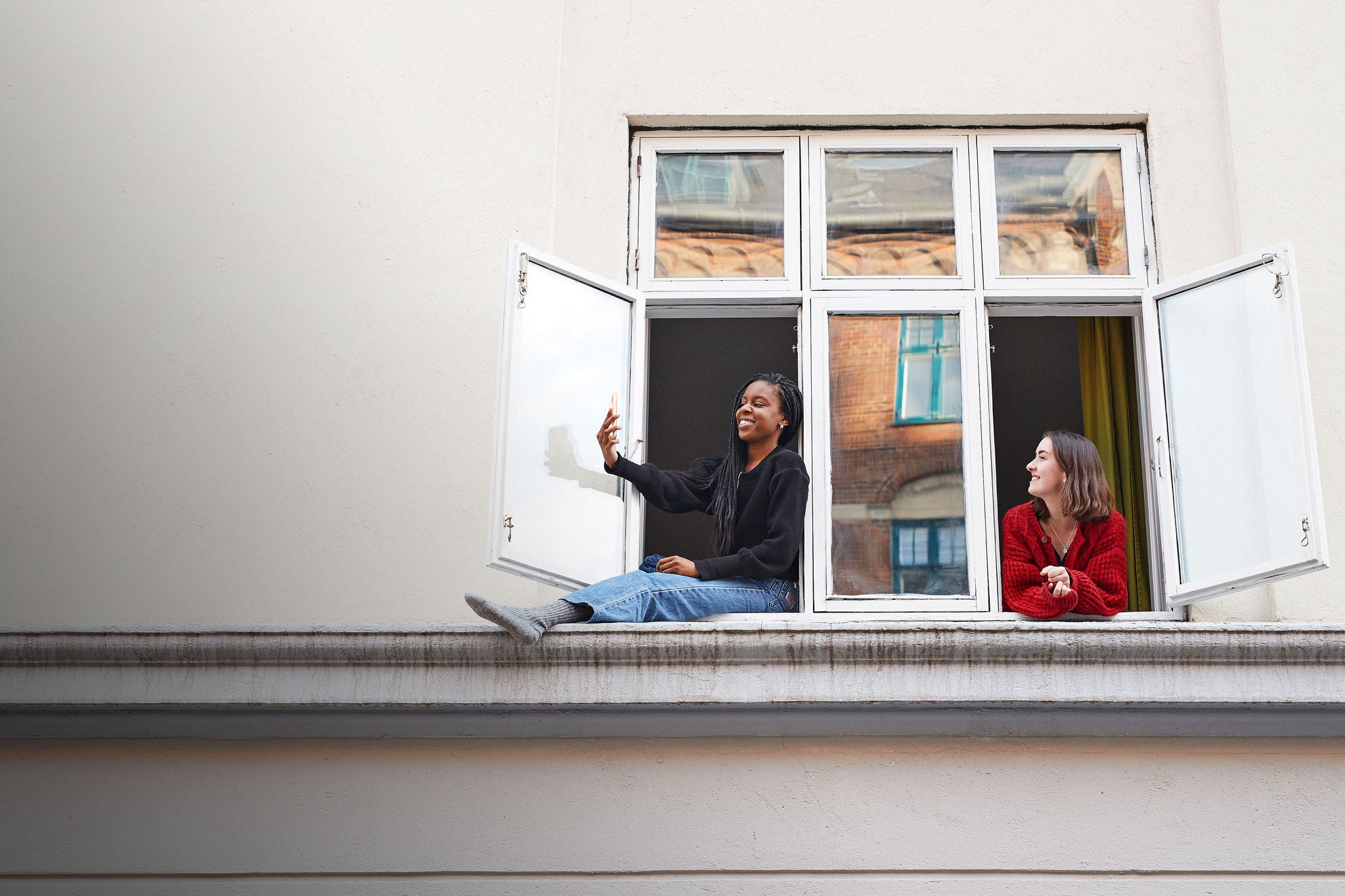 Woman taking selfie in window.