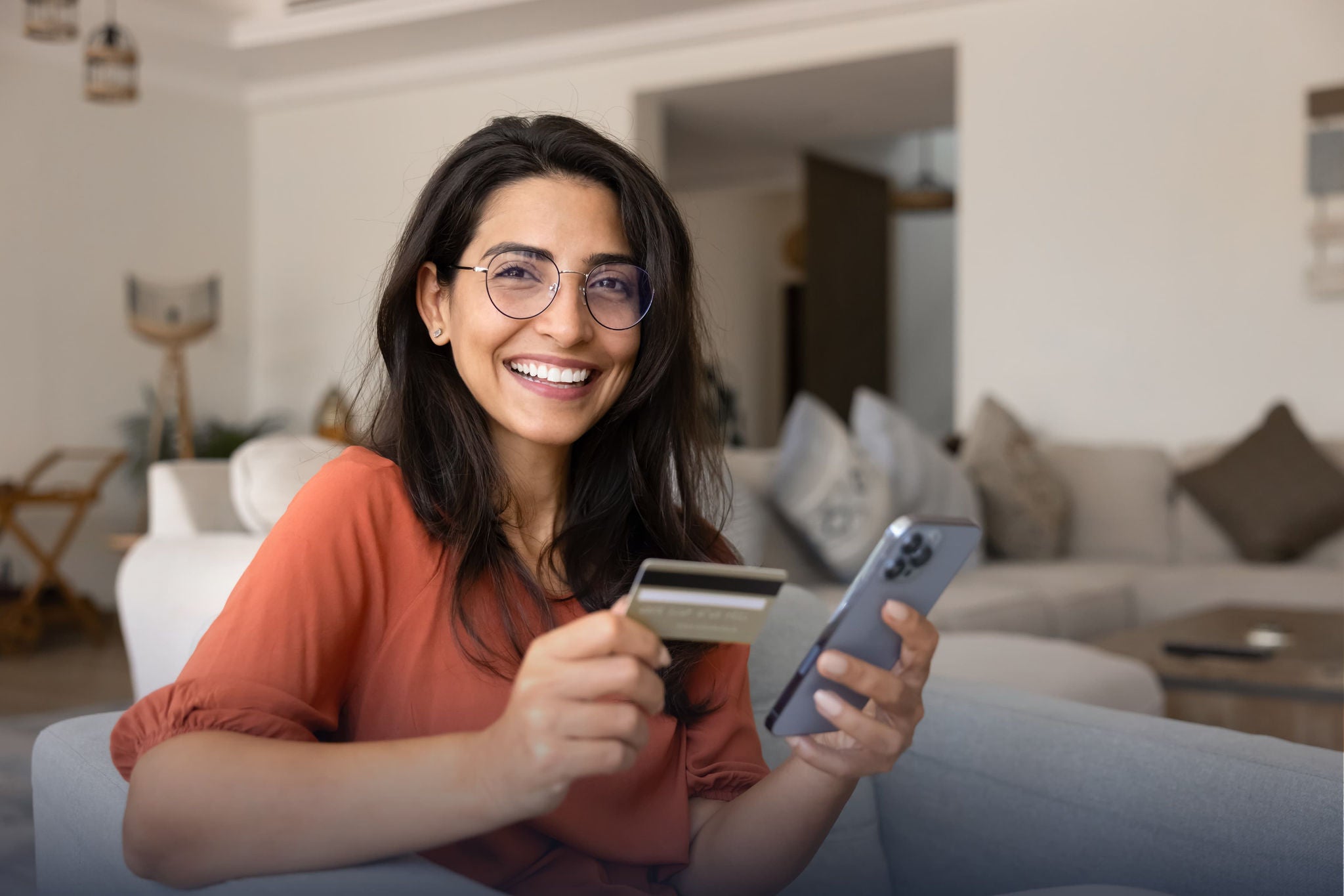Smiling woman holding a smartphone and payment card.
