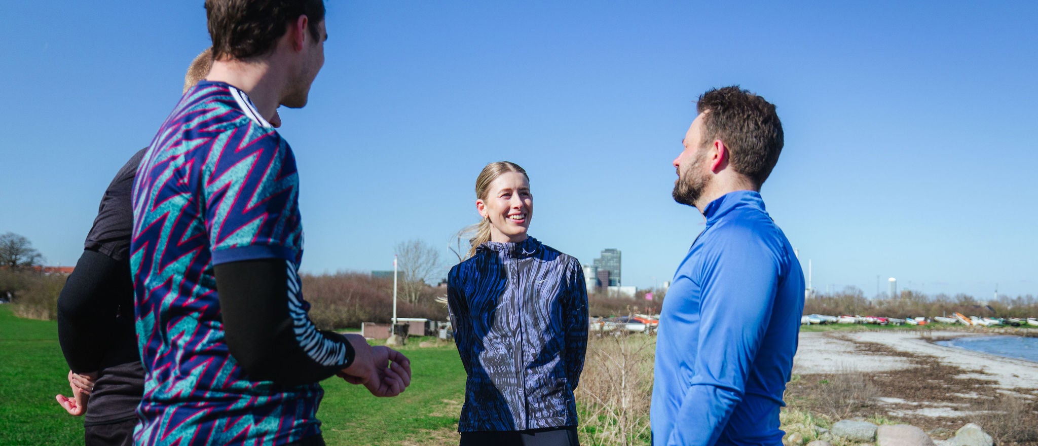 Colleagues stand together outdoors, talking during a casual group activity near the water.