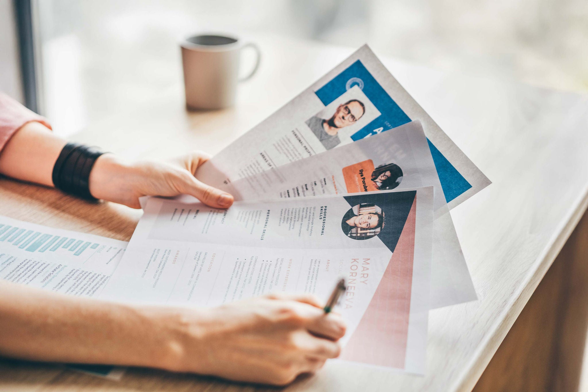 Person sichtet und prüft Lebensläufe auf einem Tisch