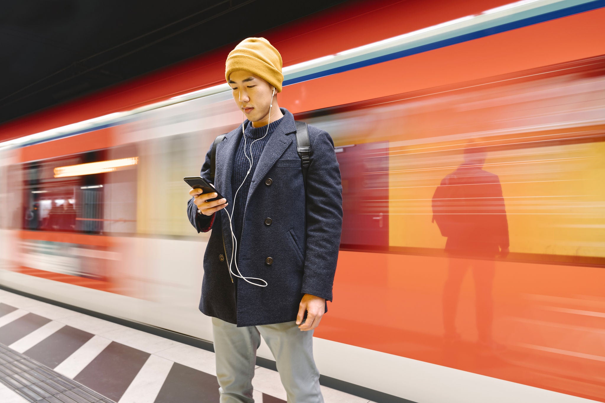 Stylish man with smartphone and earphones in metro station
