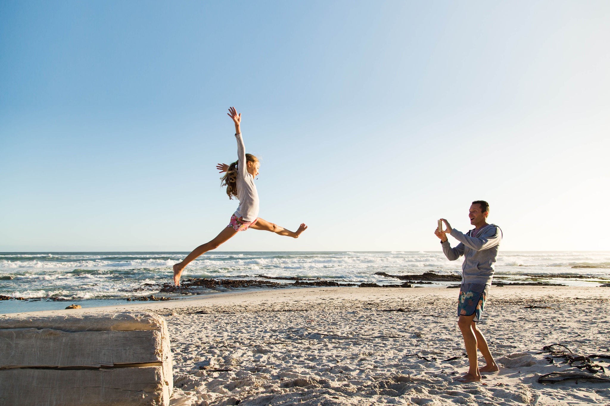 Father taking photos daughter playing beach