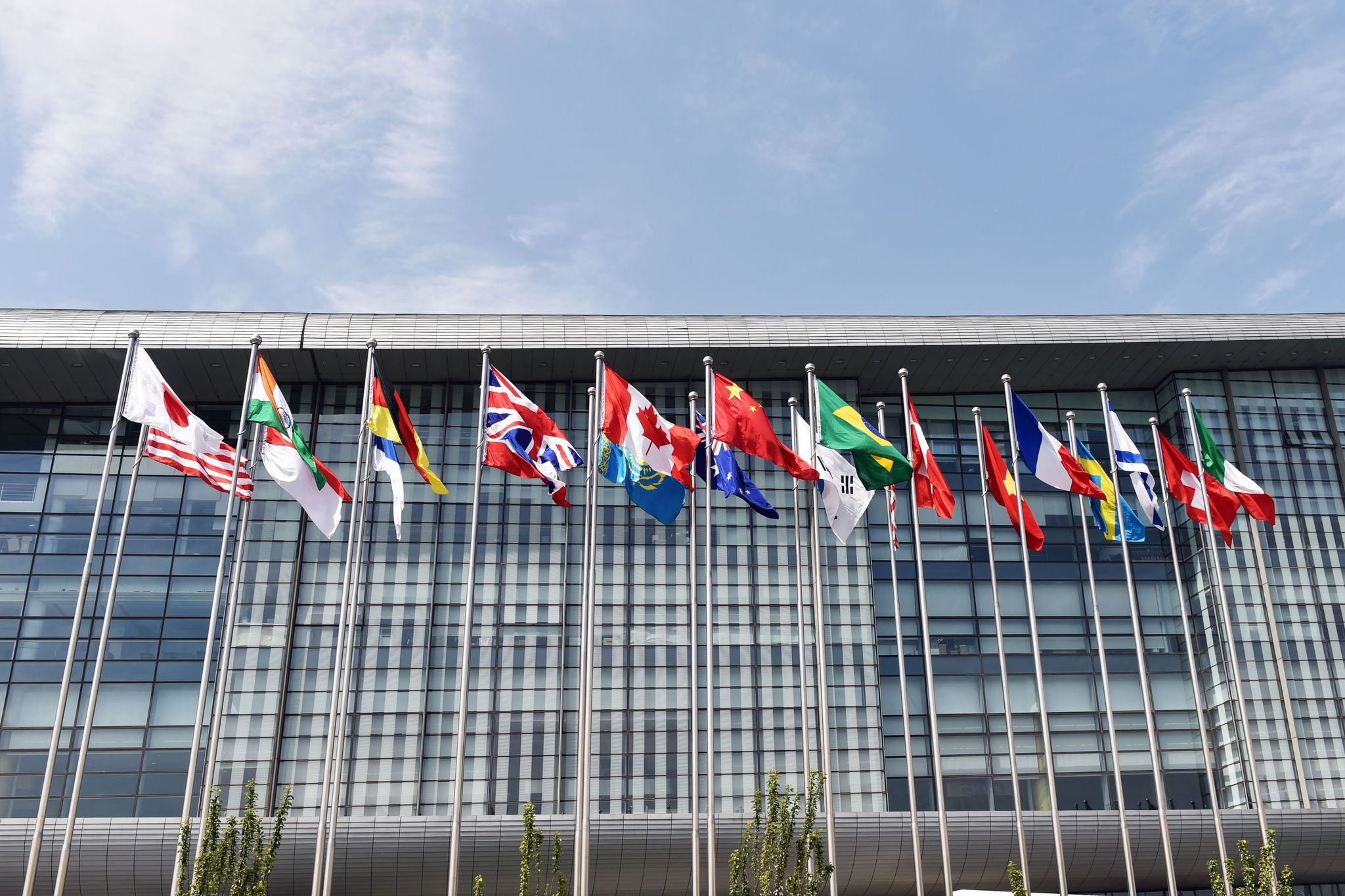 Drapeaux internationaux devant un bâtiment moderne en verre
