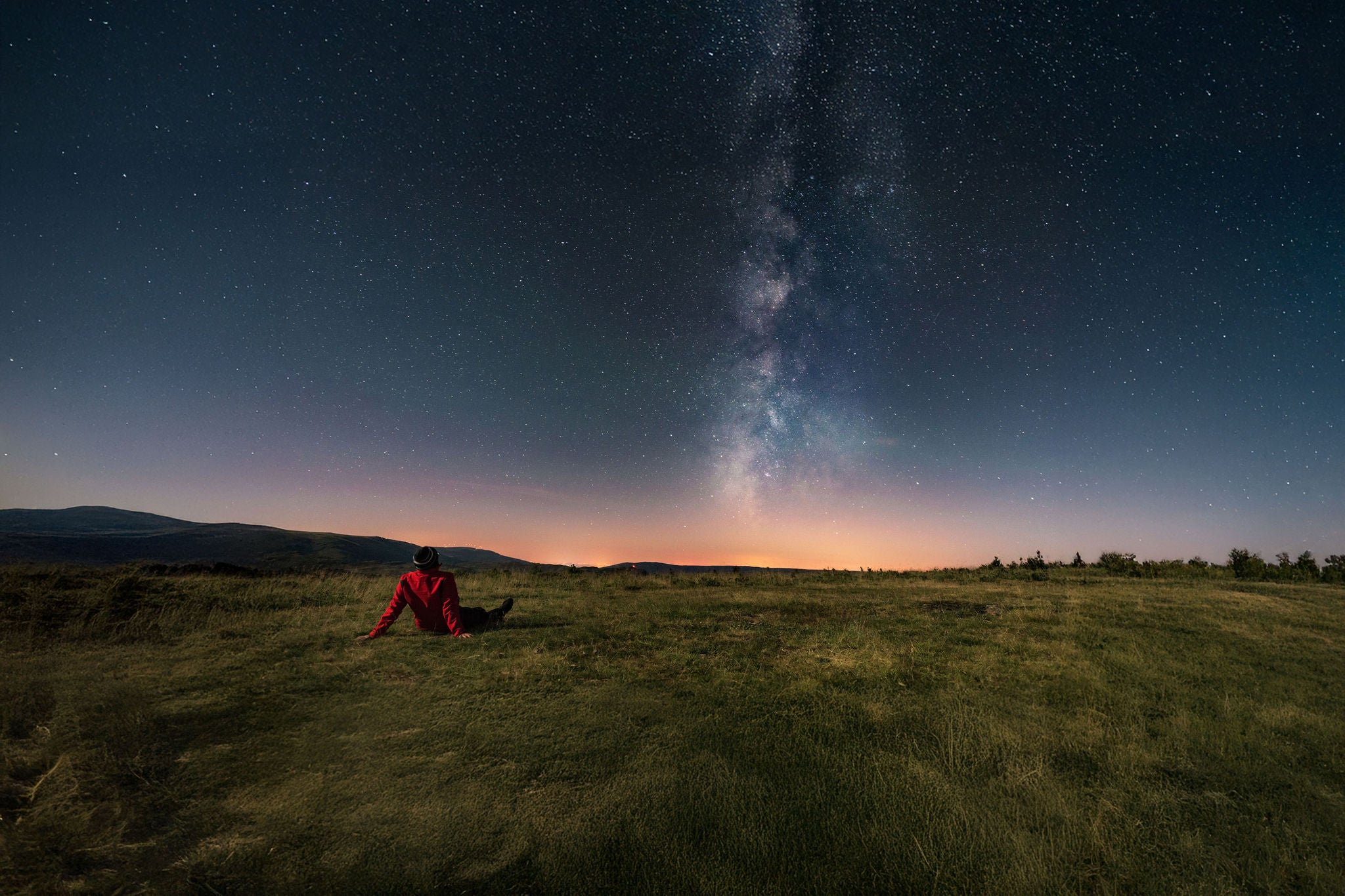 A young man lying on the grass and watching the Milky Way