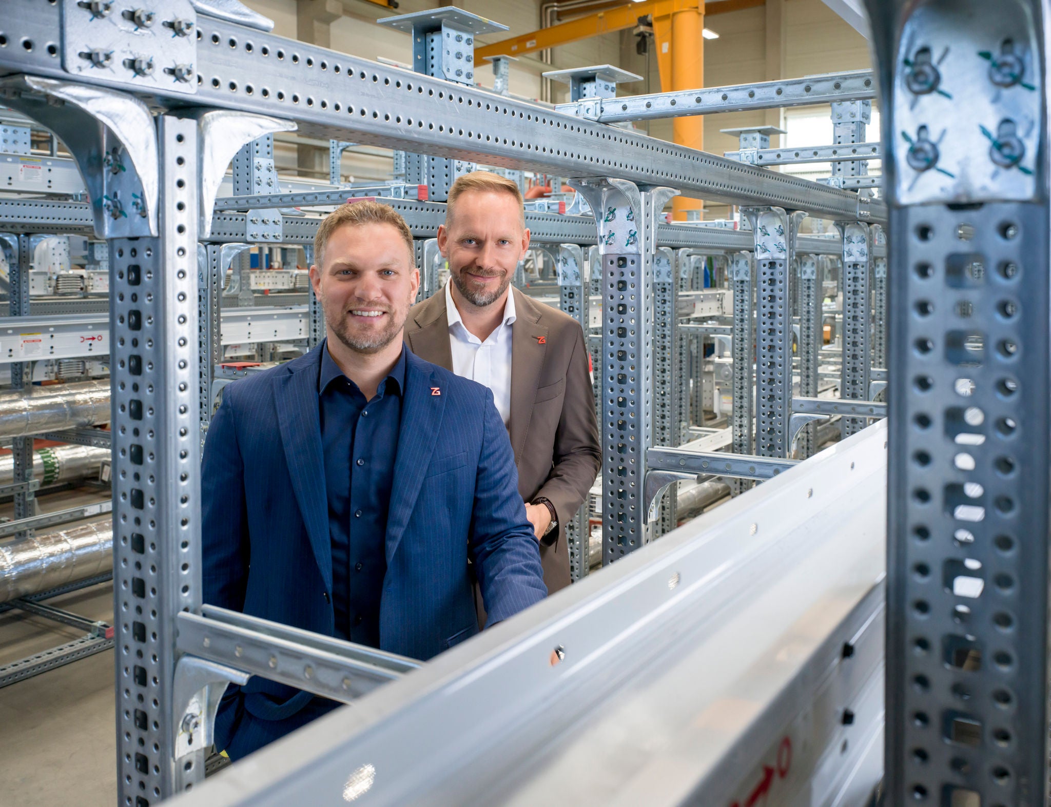 Zwei Unternehmer in Produktionshalle stehend zwischen Metallgerüst