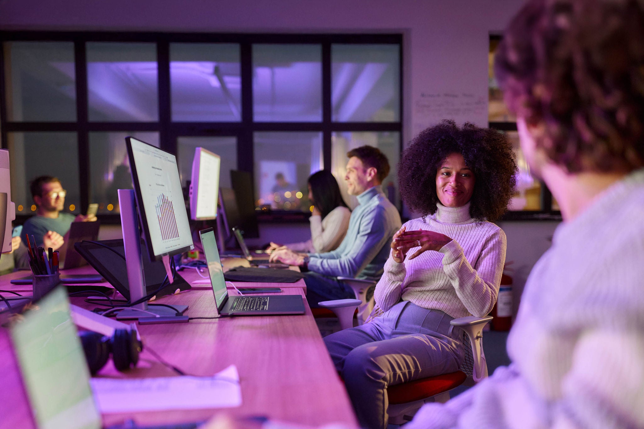 Smiling African American graphic designer communicating with her colleague.