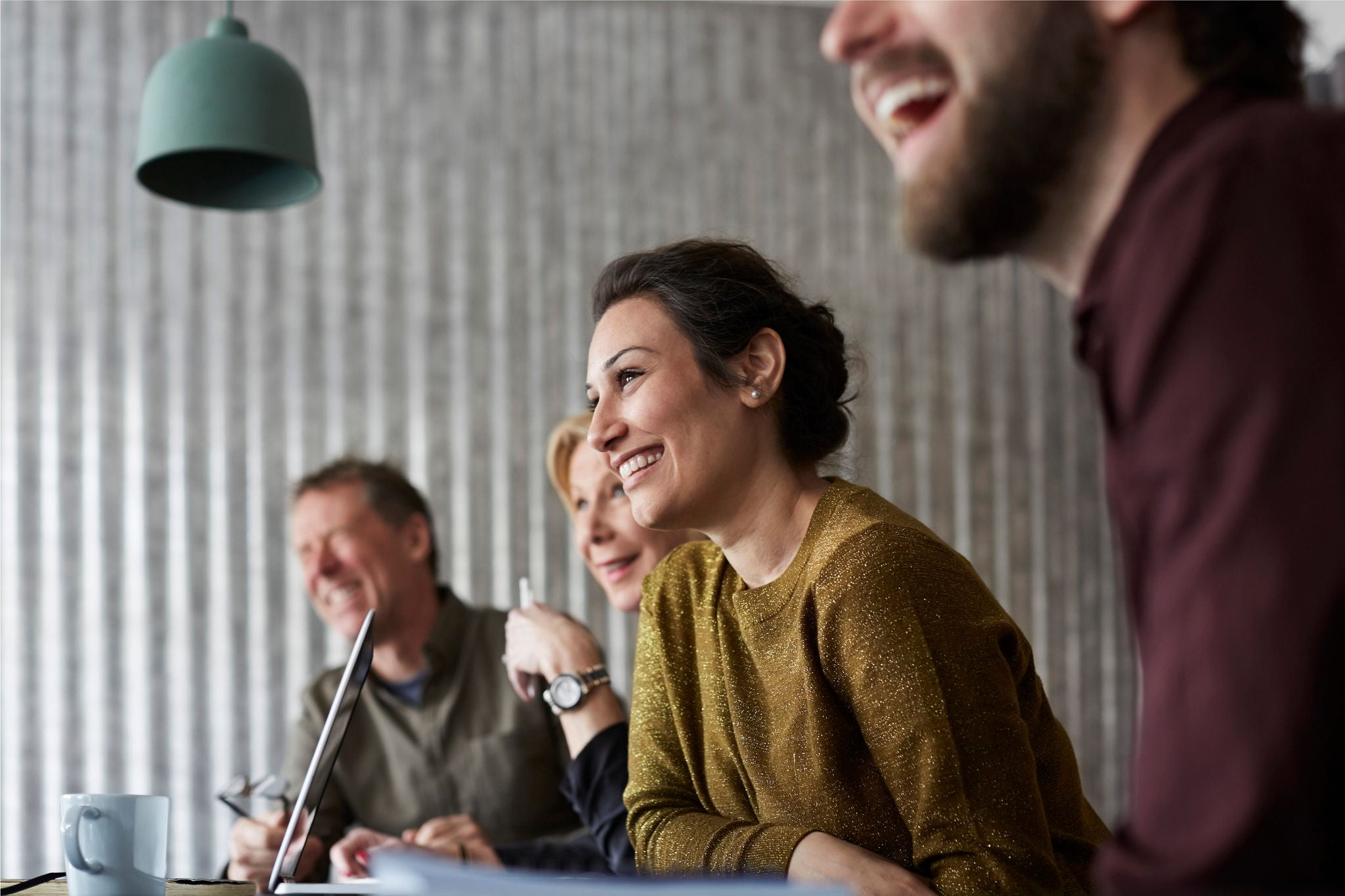 Glada kreativa affärskollegor som sitter vid konferensbordet och tittar bort i styrelserummet