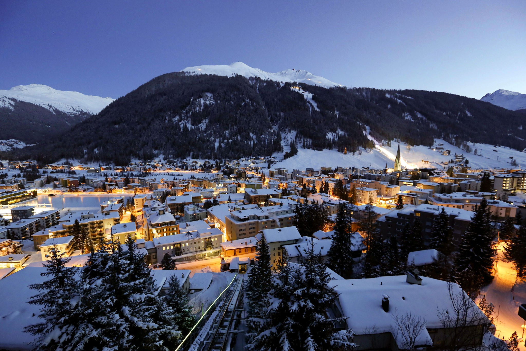 Snow covered buildings are seen at dusk from the Schatzalp area above the town of Davos, Switzerland. Photographer