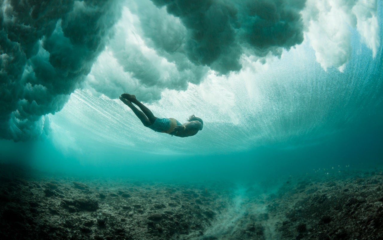 年輕男子在洶湧海洋下自由潛水，探索珊瑚礁