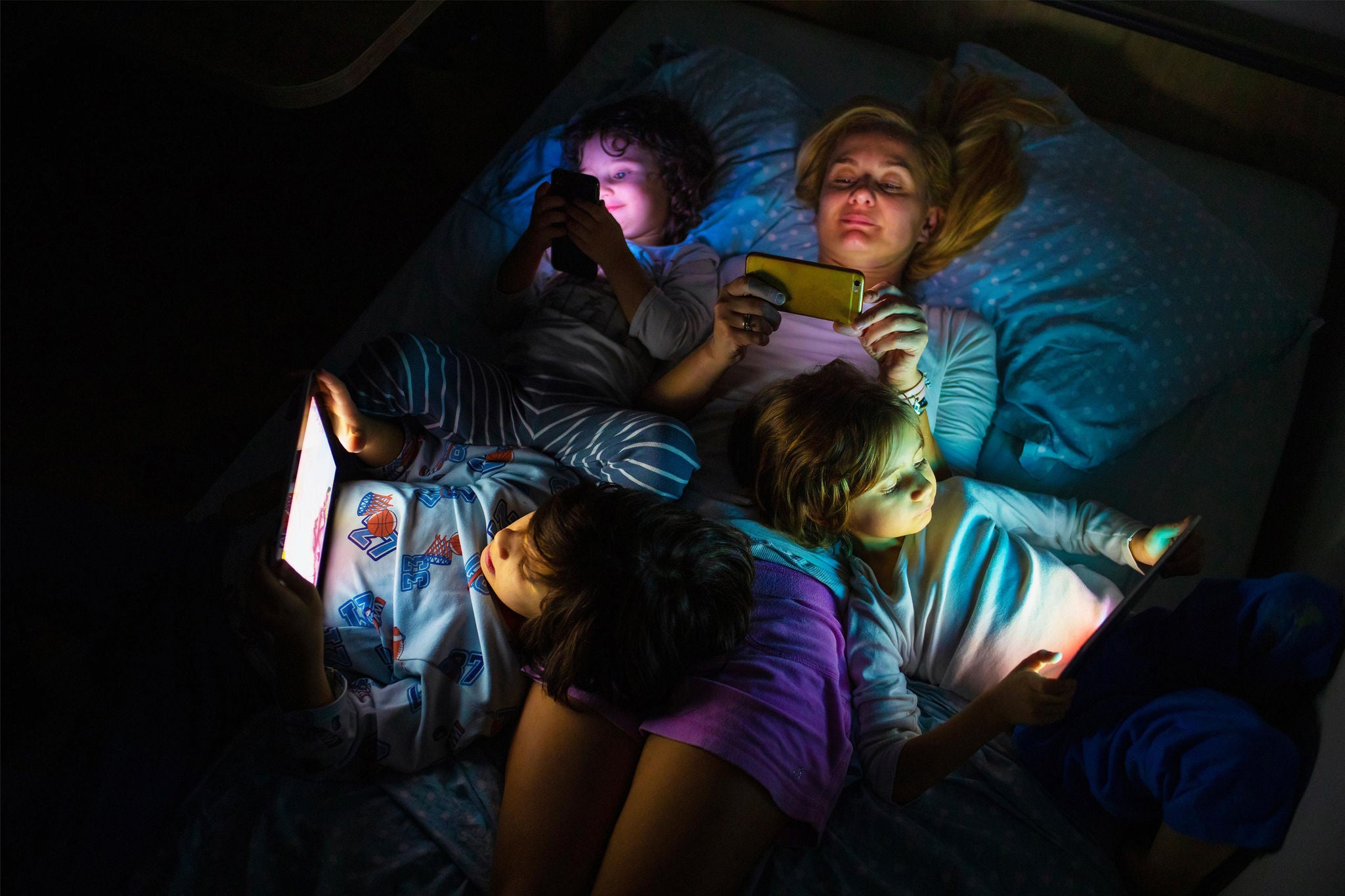 Mother with her kids looking a digital tablet in the dark