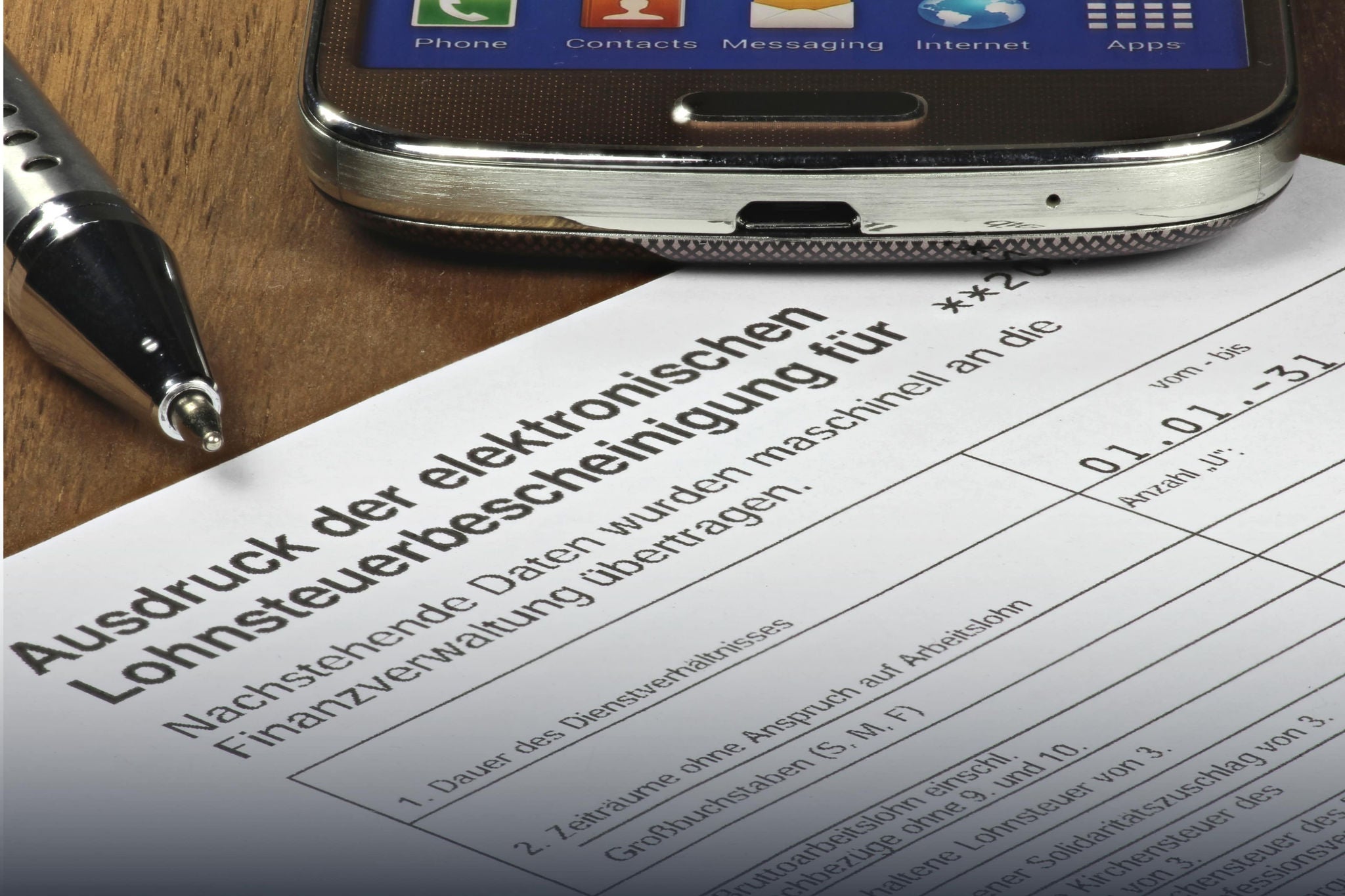 A smiling young woman with headphones and folders, standing outdoors on a college campus.