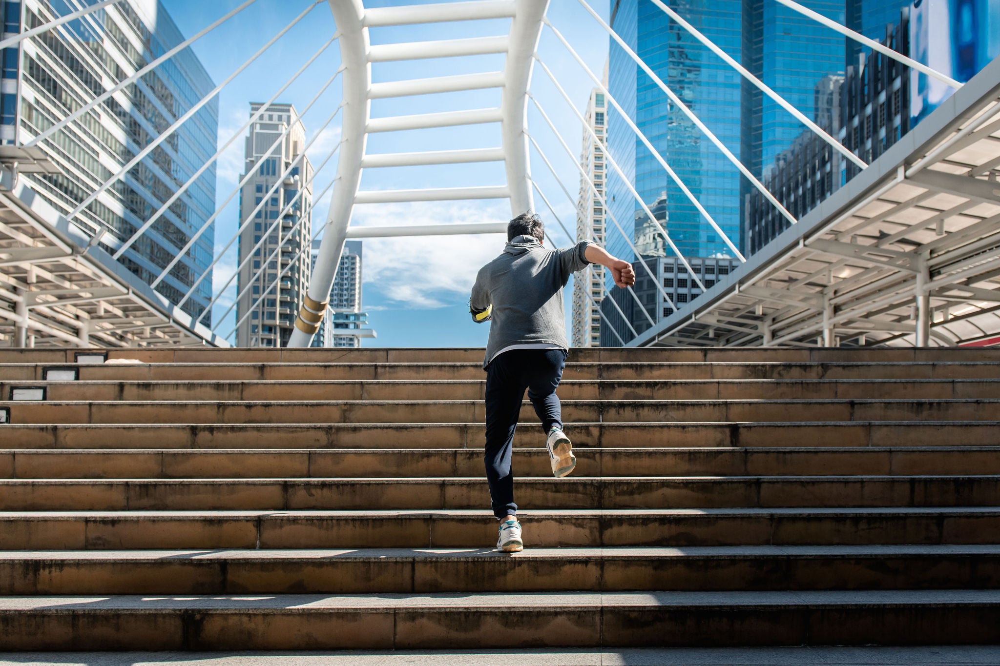 Mies juoksee portaita ylös kohti siltaa