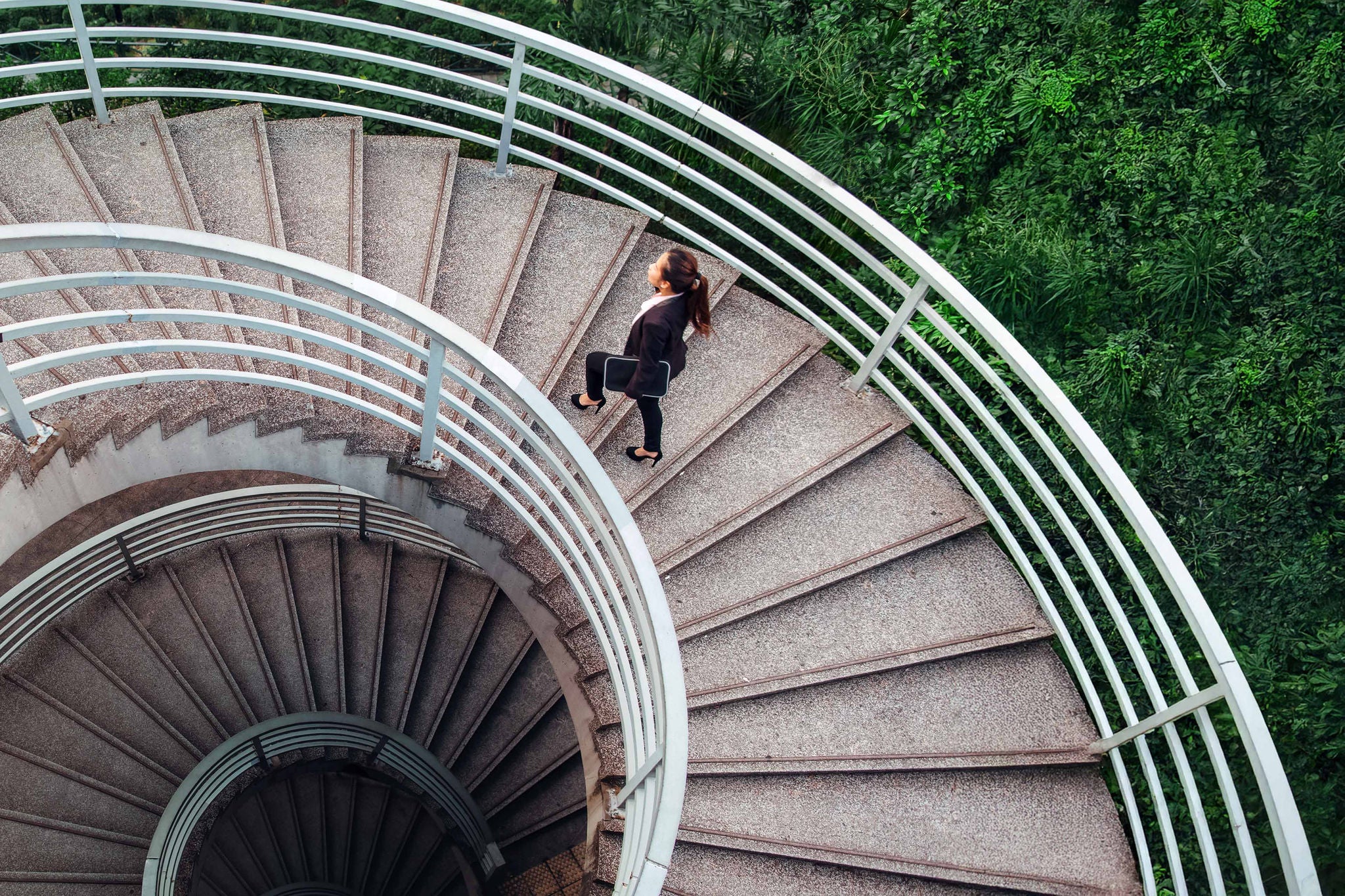 Business woman walking on spiral staircase in Hong Kong
