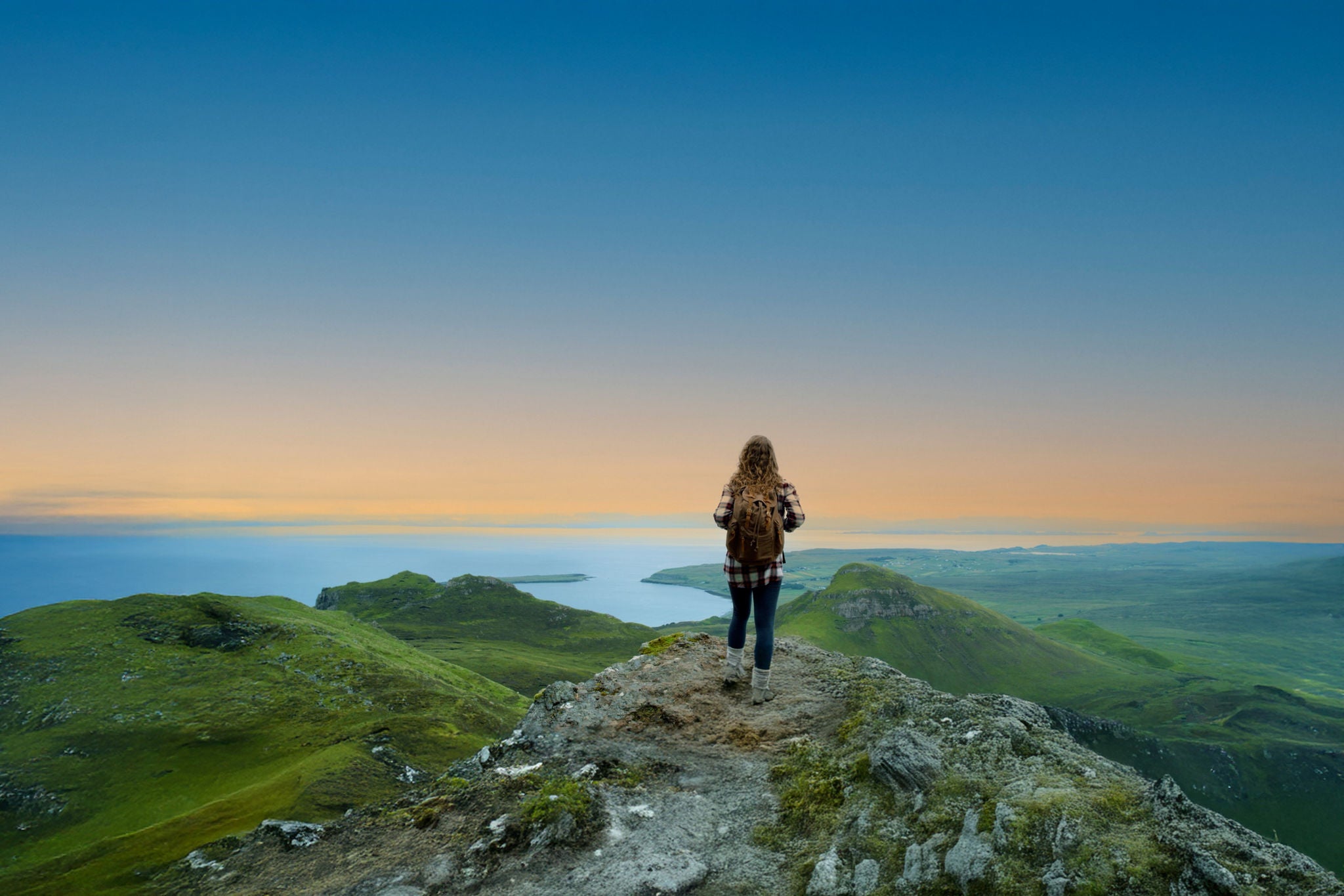 Hiker overlooking a coastal landscape from a mountain summit
