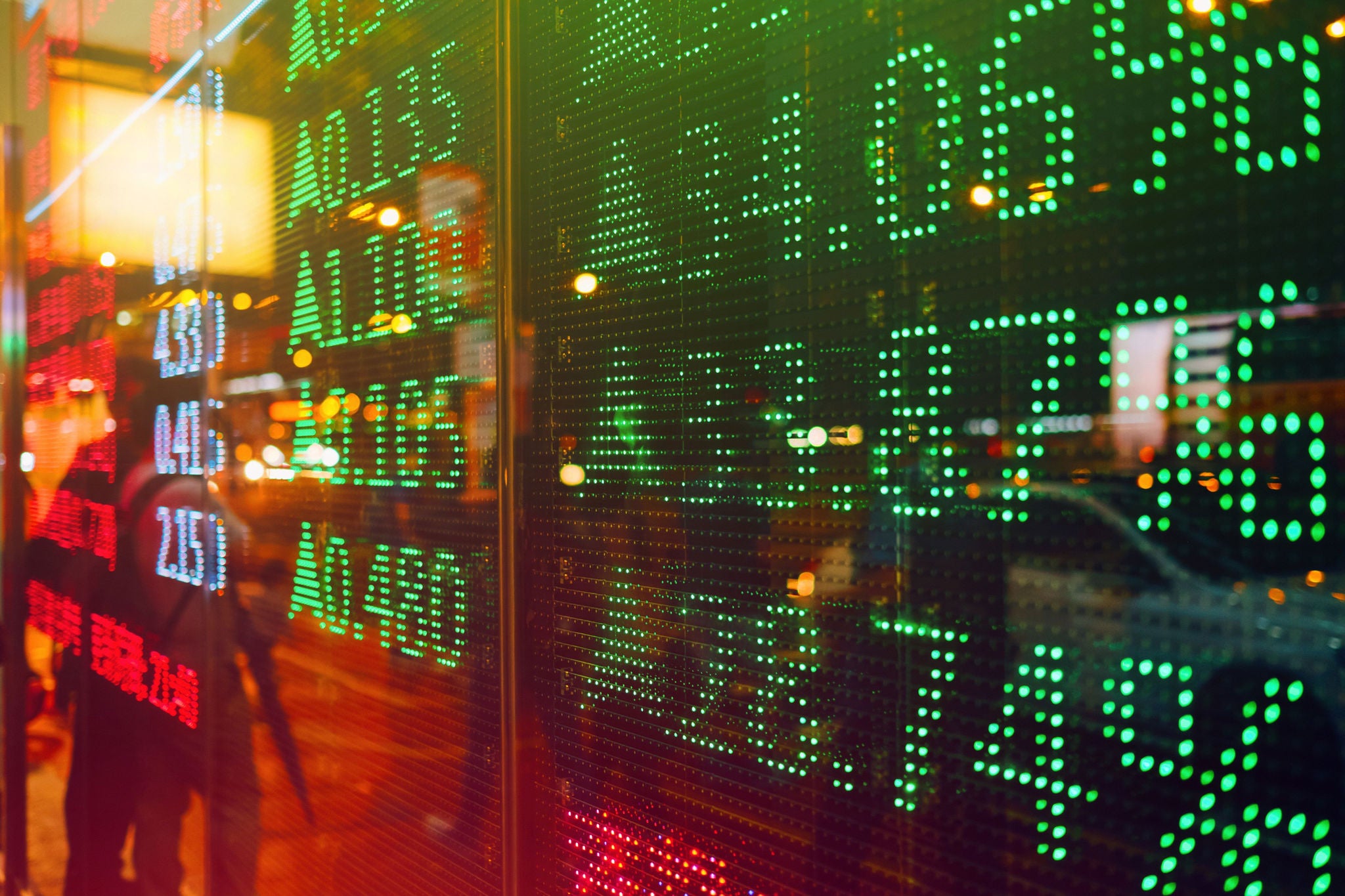 Street display board showing stock prices rising in green