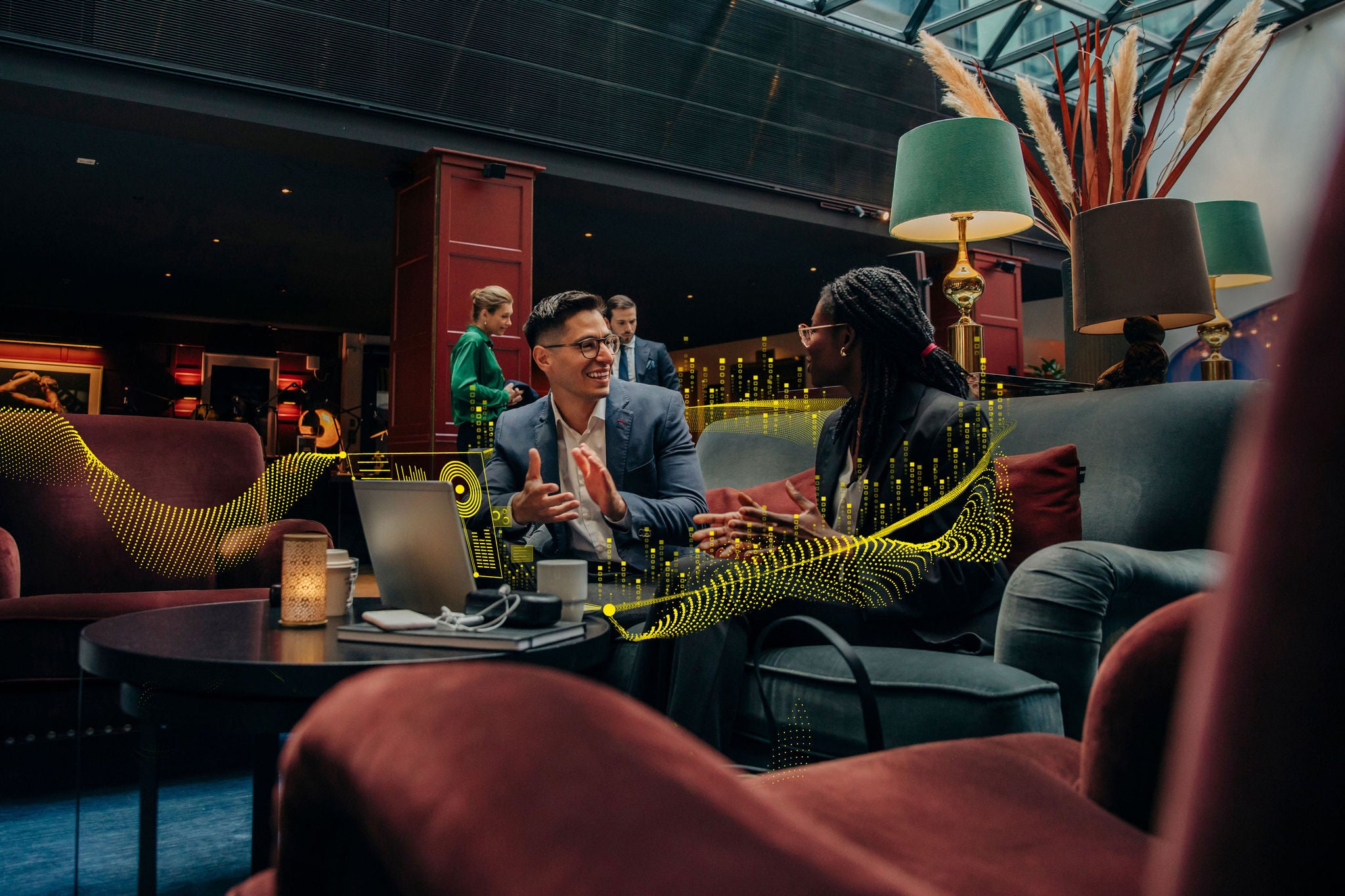 Smiling male professional discussing with female colleague sitting in hotel lounge