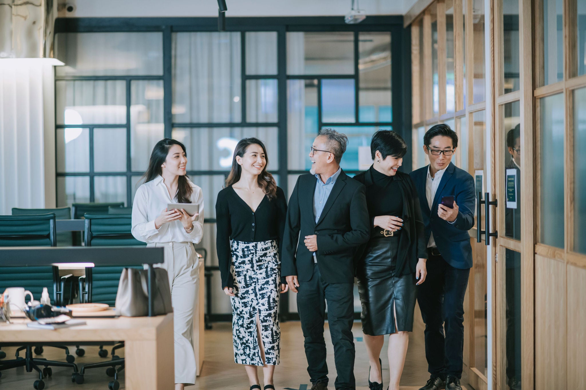 group of asian chinese successful office management team having discussion while walking toward camera