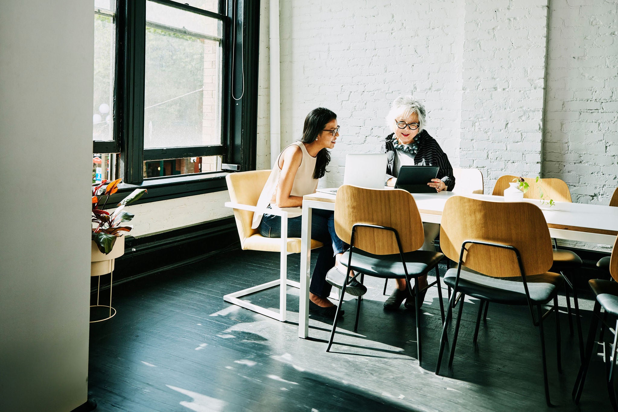 Senior businesswoman presenting project on digital tablet to colleague in conference room