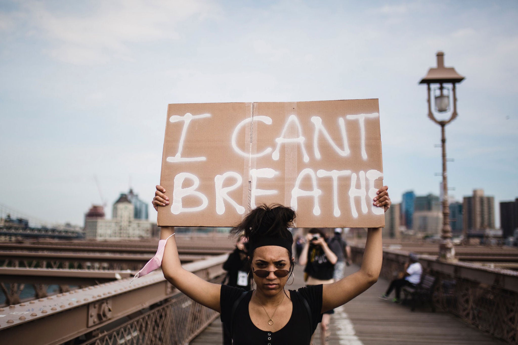 Black woman holding sign, I can't breathe, walking on bridge