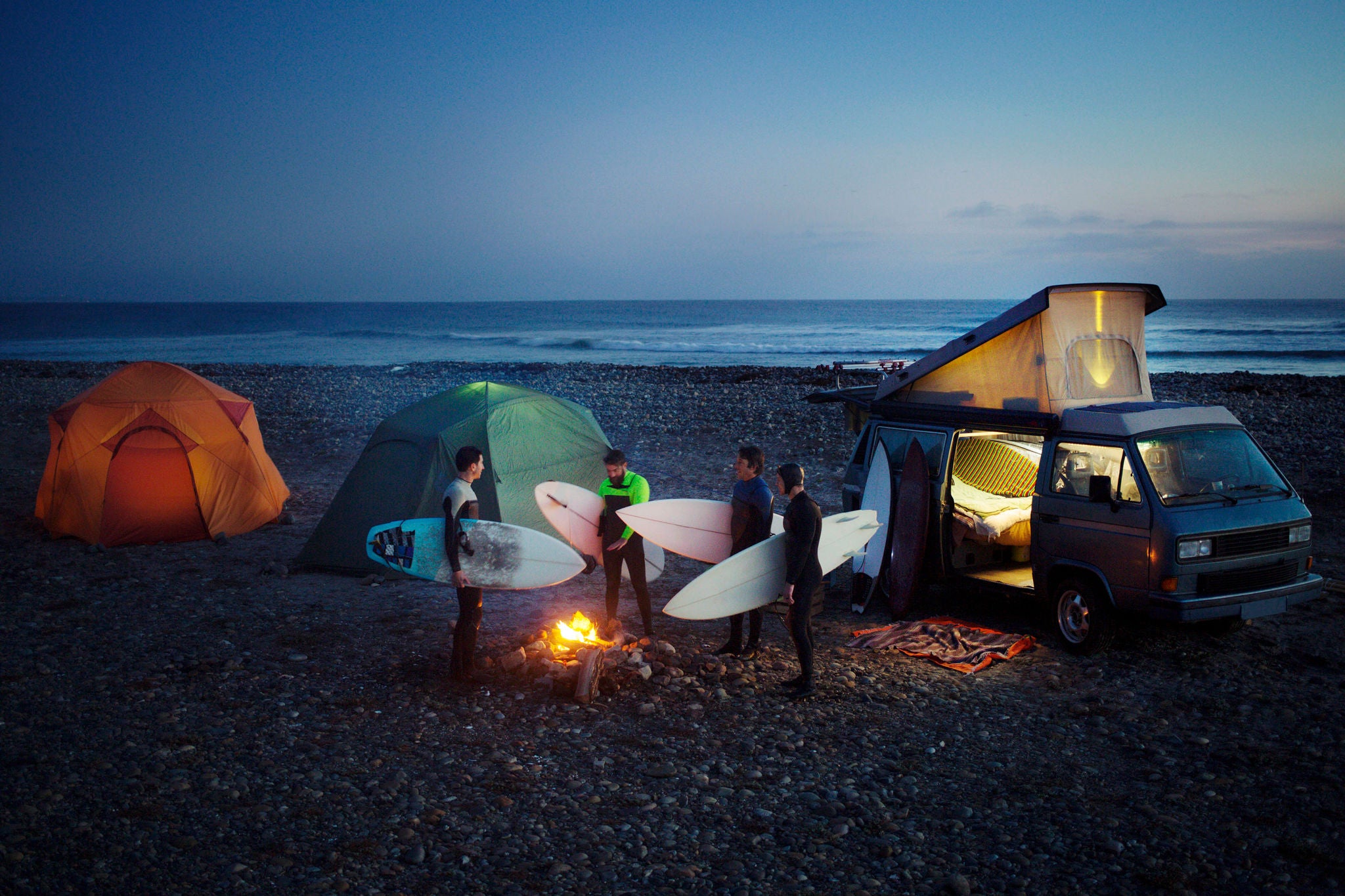 Surfers talk beach camp fire camper vans