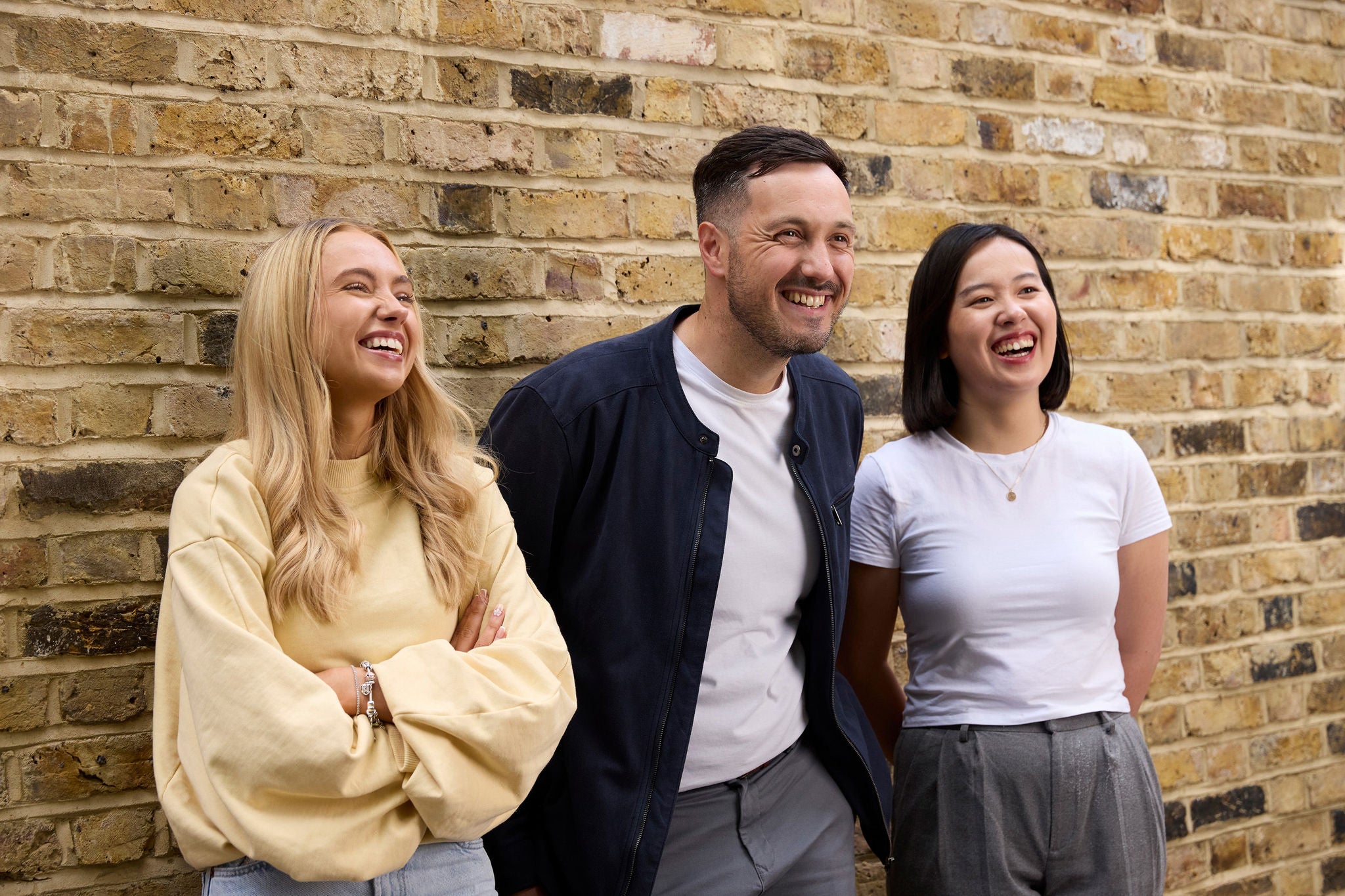 Three people standing in front of a brick wall