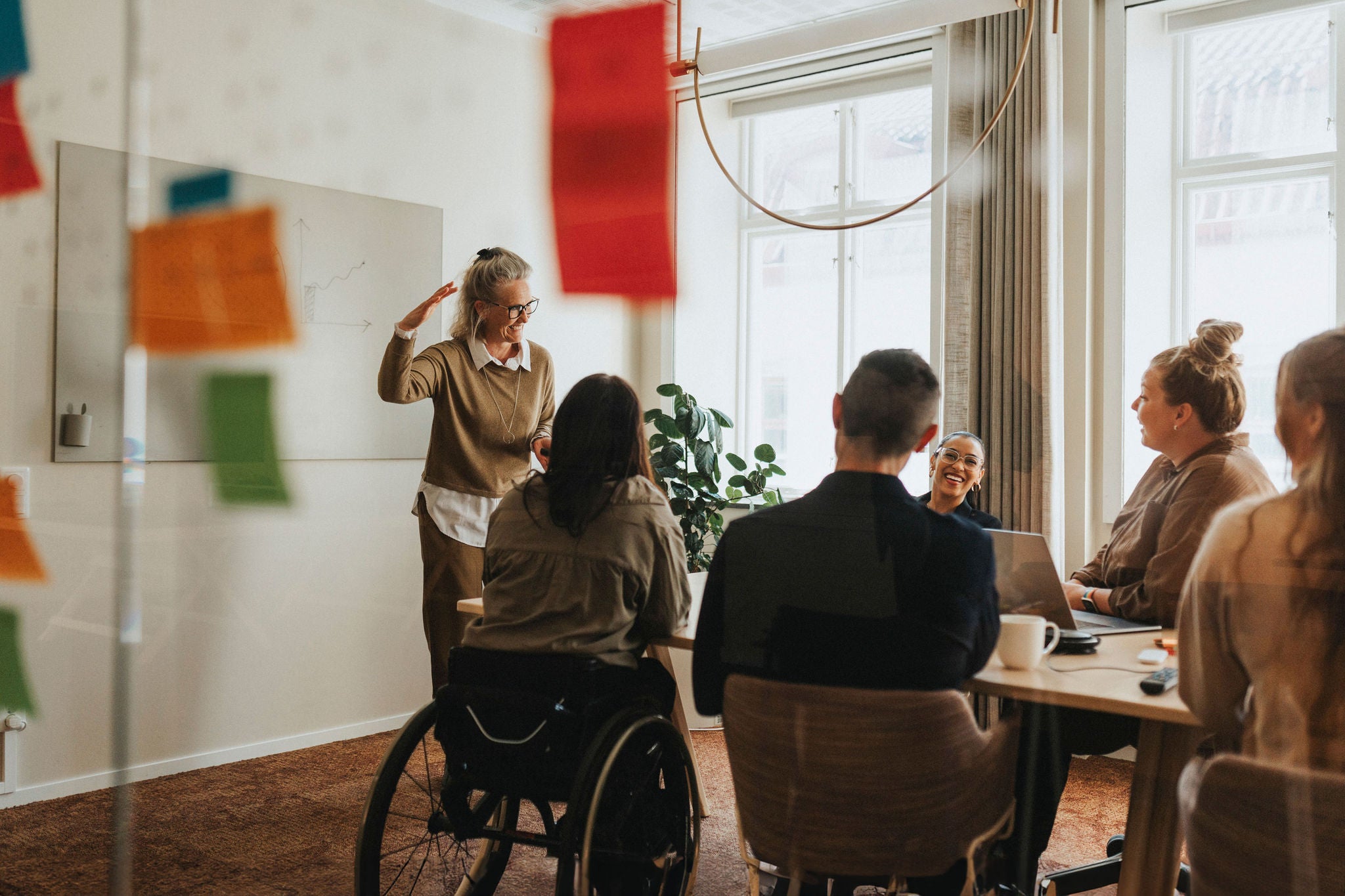 Happy female business professional explaining ideas to colleagues in meeting room