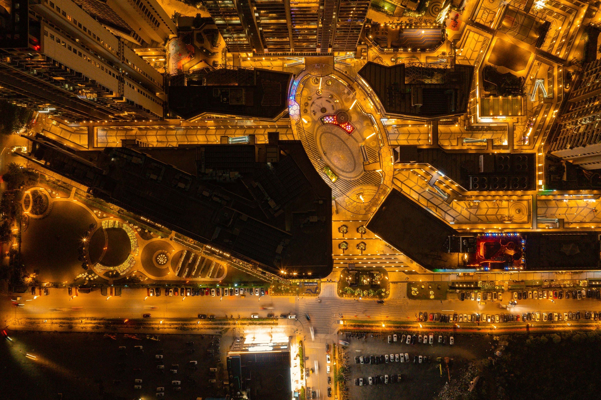 Aerial view of a modern city illuminated by warm streetlights, showing a geometric network of roads and buildings, Golf Course Extension Road, Gurugram, Haryana, India.
