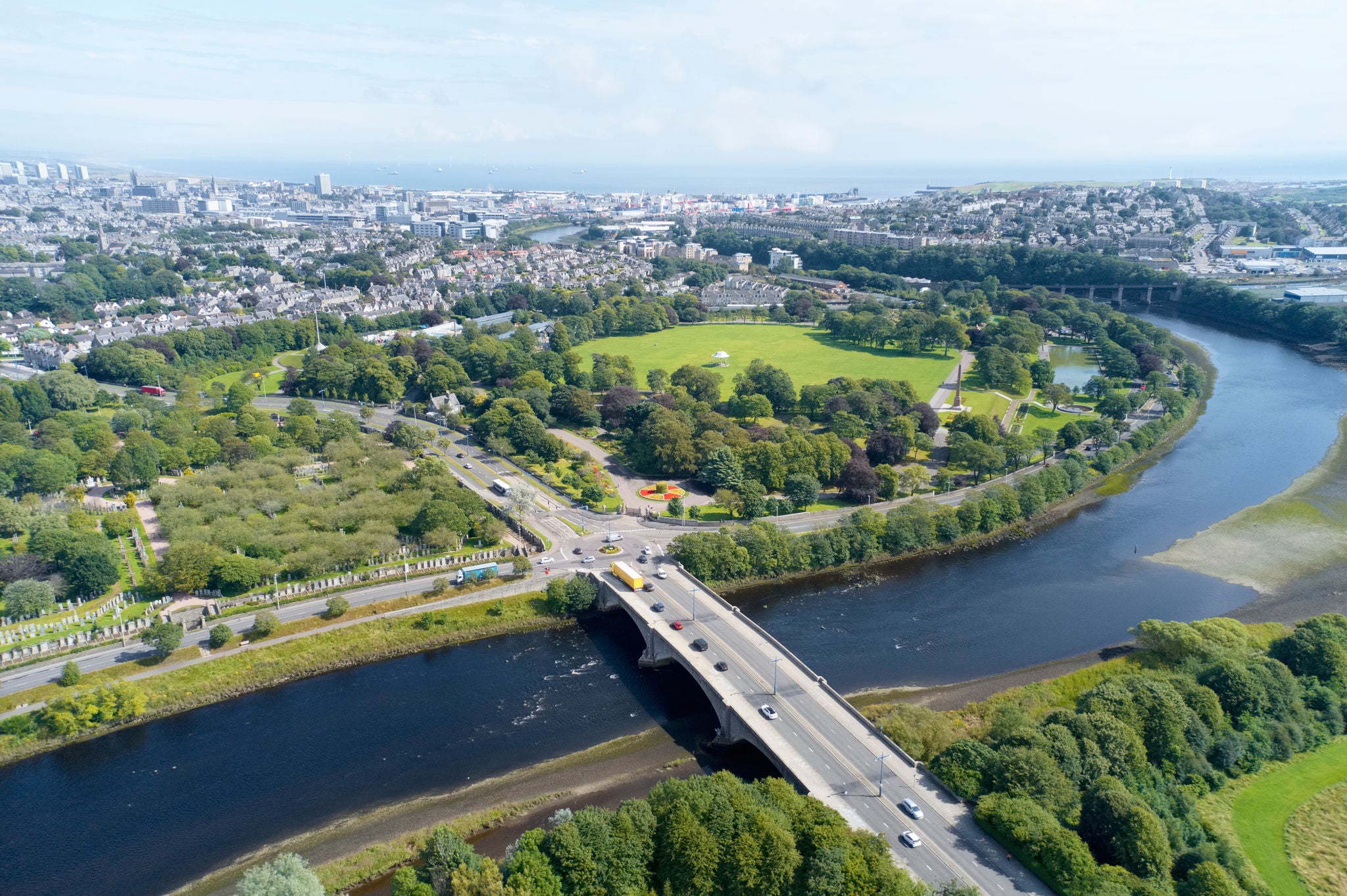 Aerial view of a river, bridge and green parkland