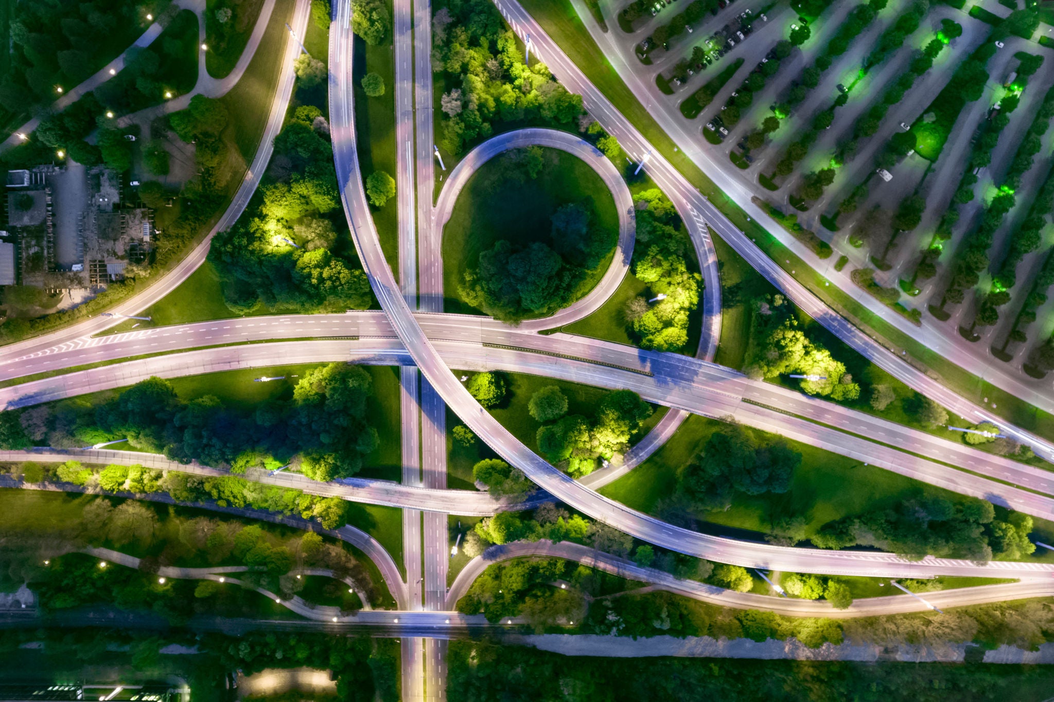 Aerial view of illuminated roads and intersections surrounded by green spaces at night