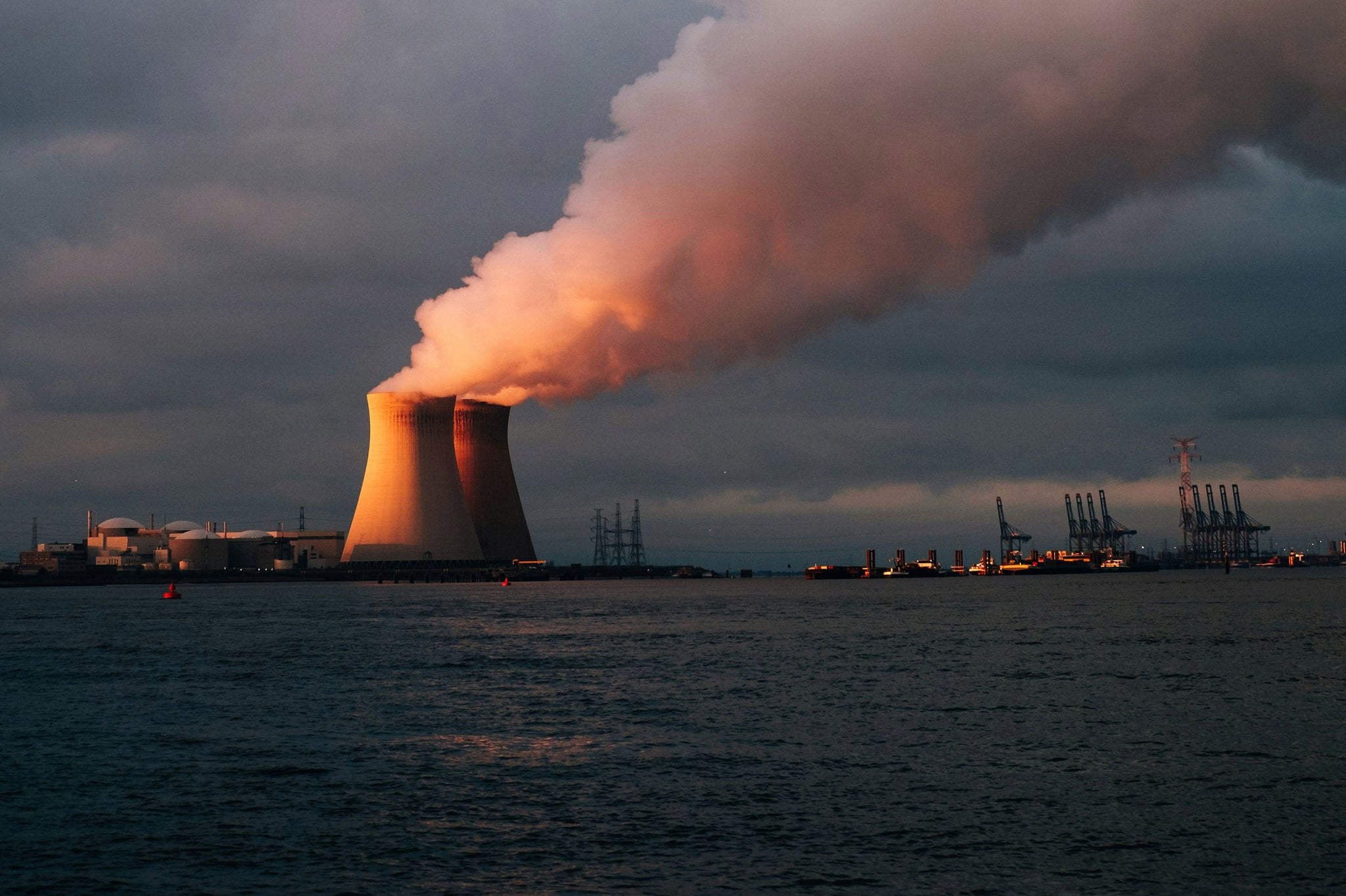Nuclear power plant with cooling towers releasing steam at dusk