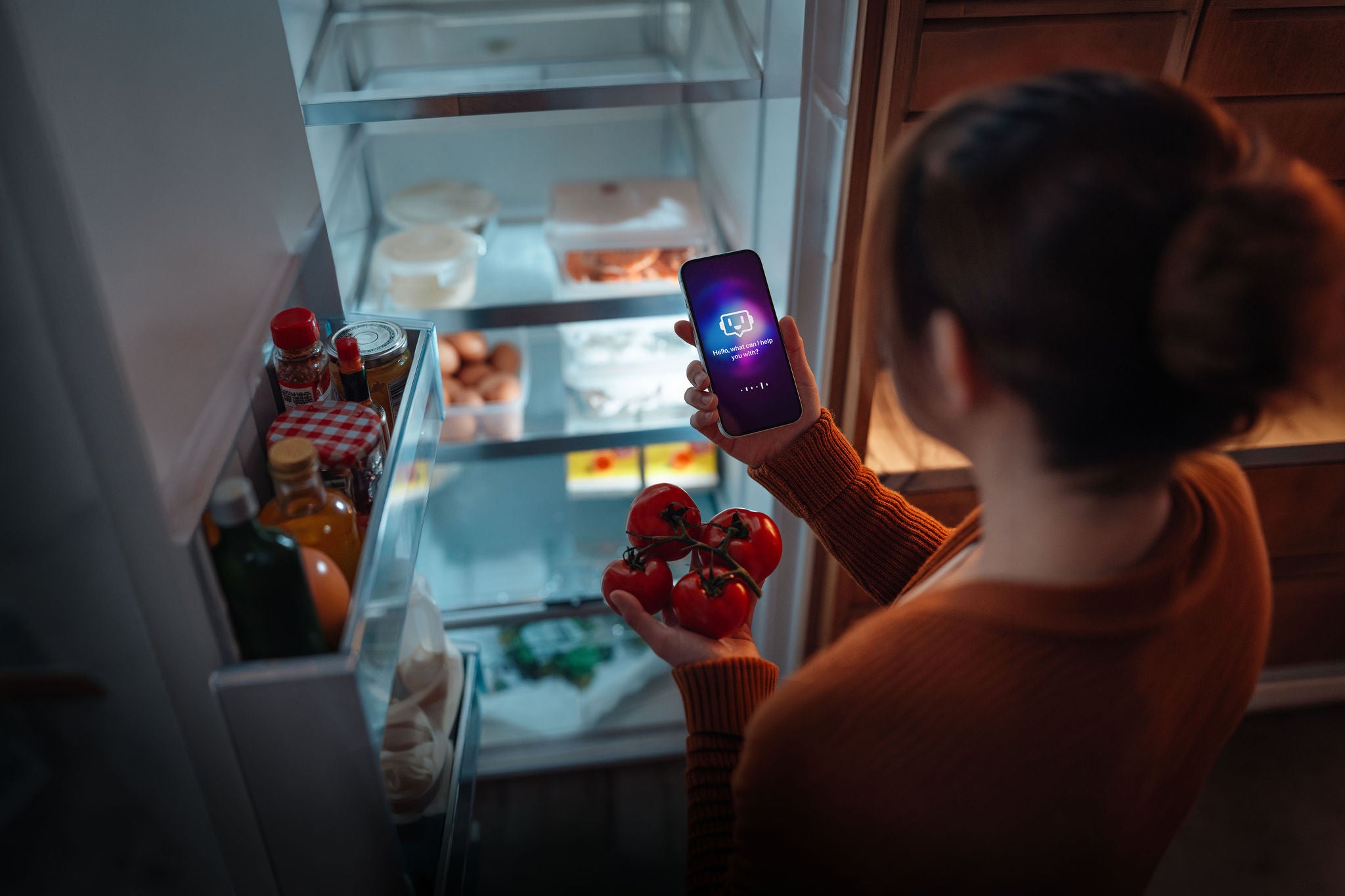 Woman using AI technology on smartphone to track fridge inventory