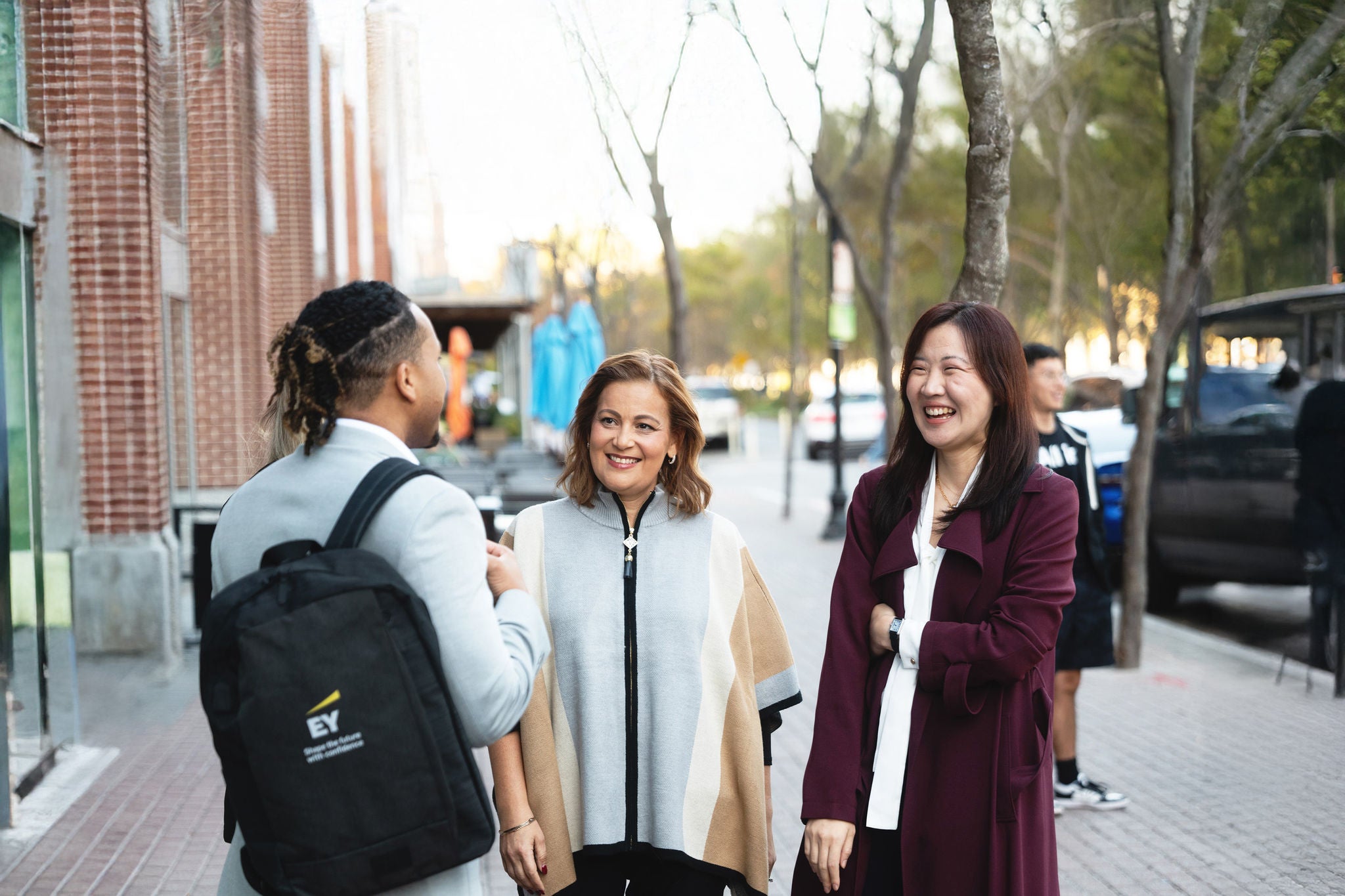 EY people smiling while having a conversation outside of the office