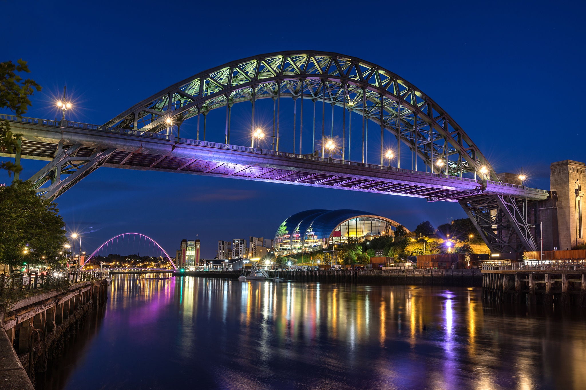 Tyne Bridge over river with Newcastle city skyline at night