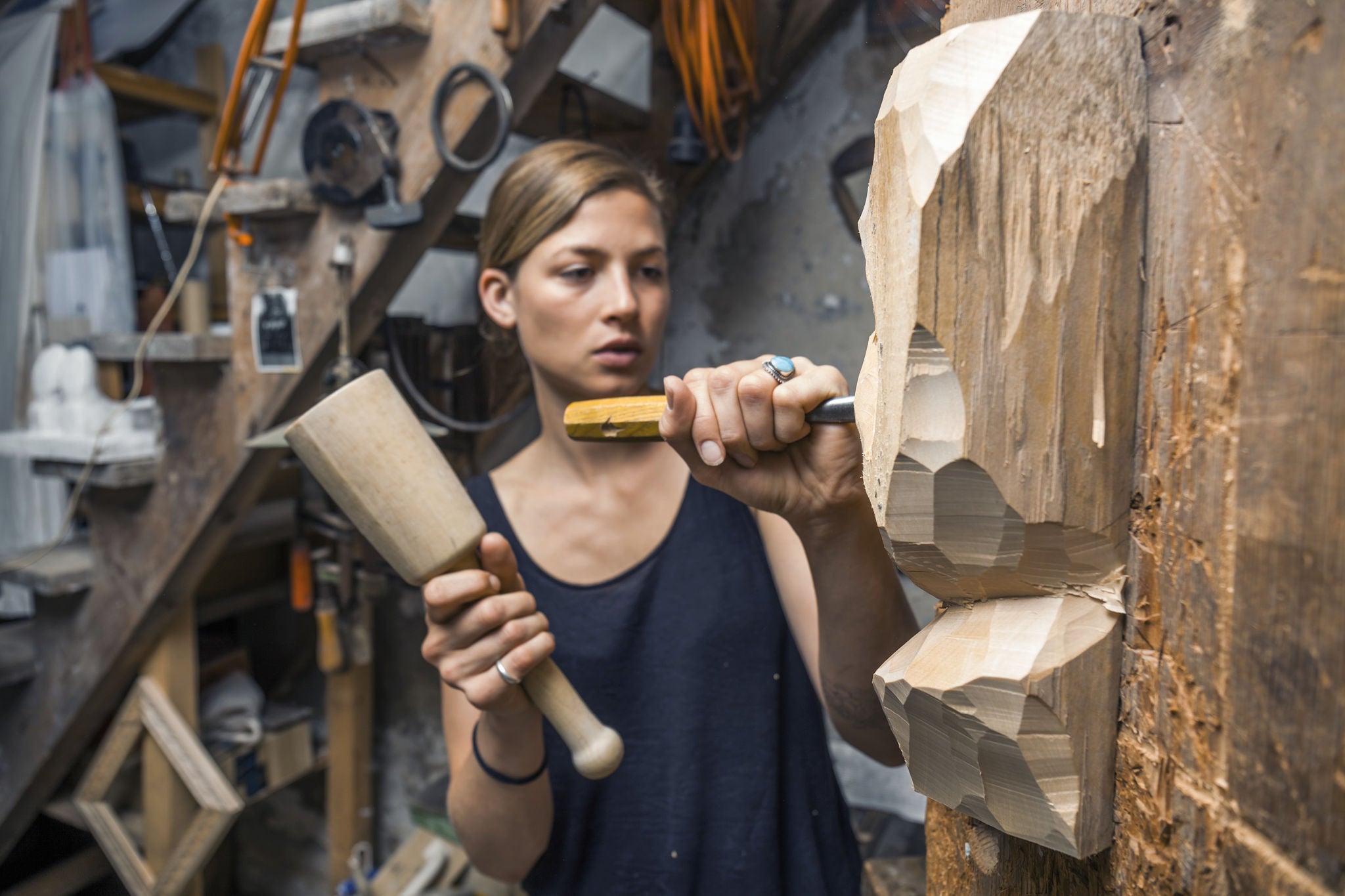 Sculptress carving wooden figure in workshop