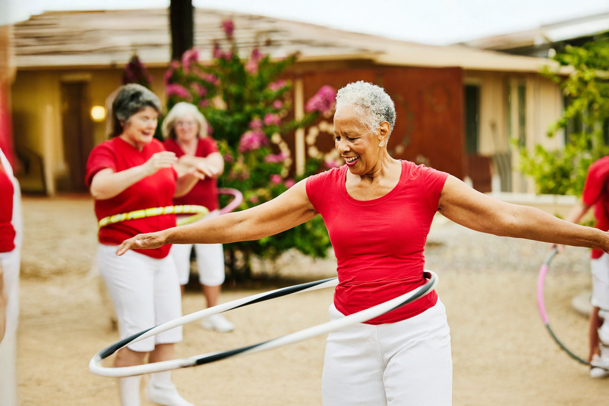 Lächelnde Seniorinnen-Tanzgruppe mit sich drehenden Reifen