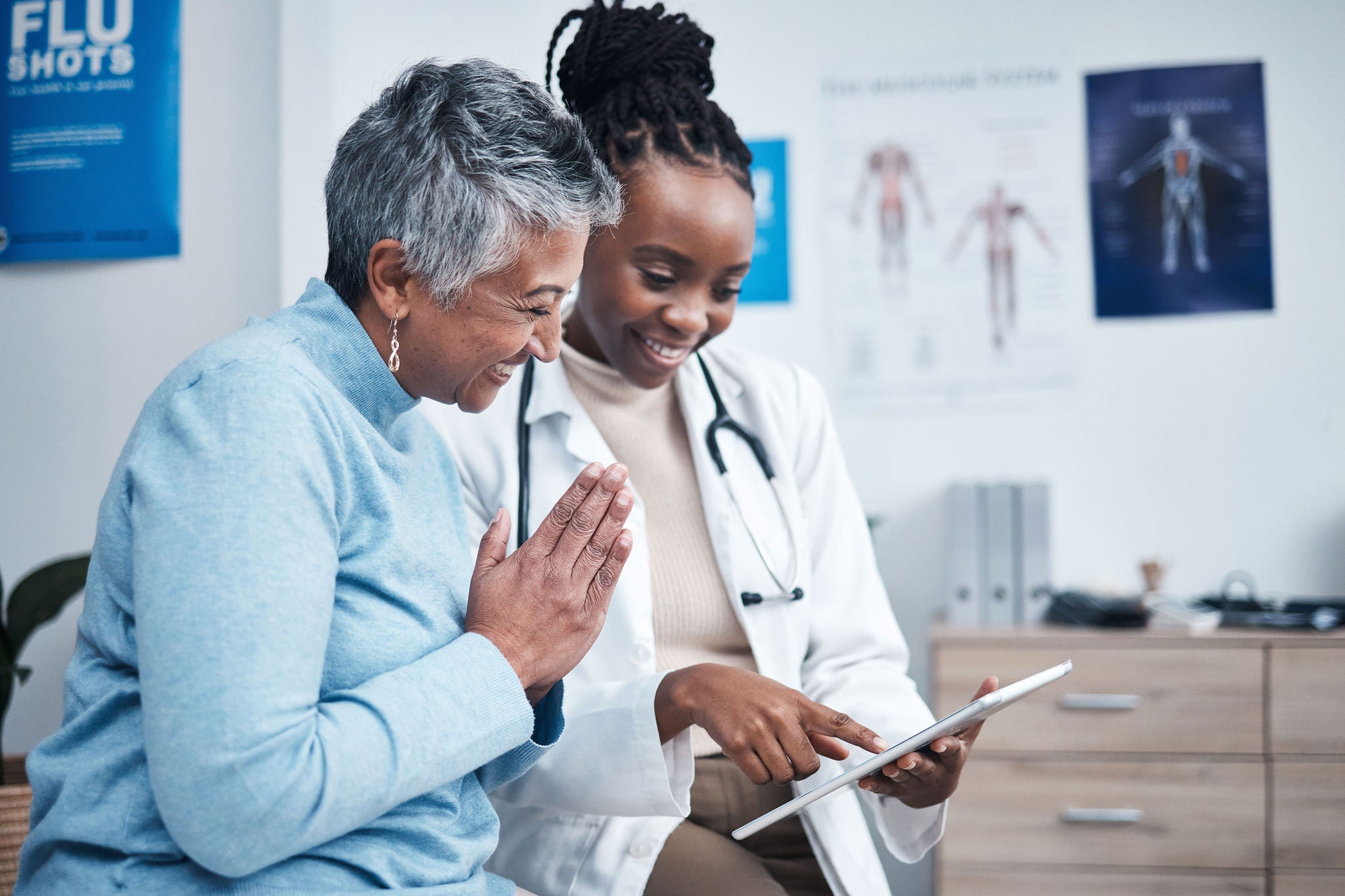 Black woman doctor and senior patient with tablet