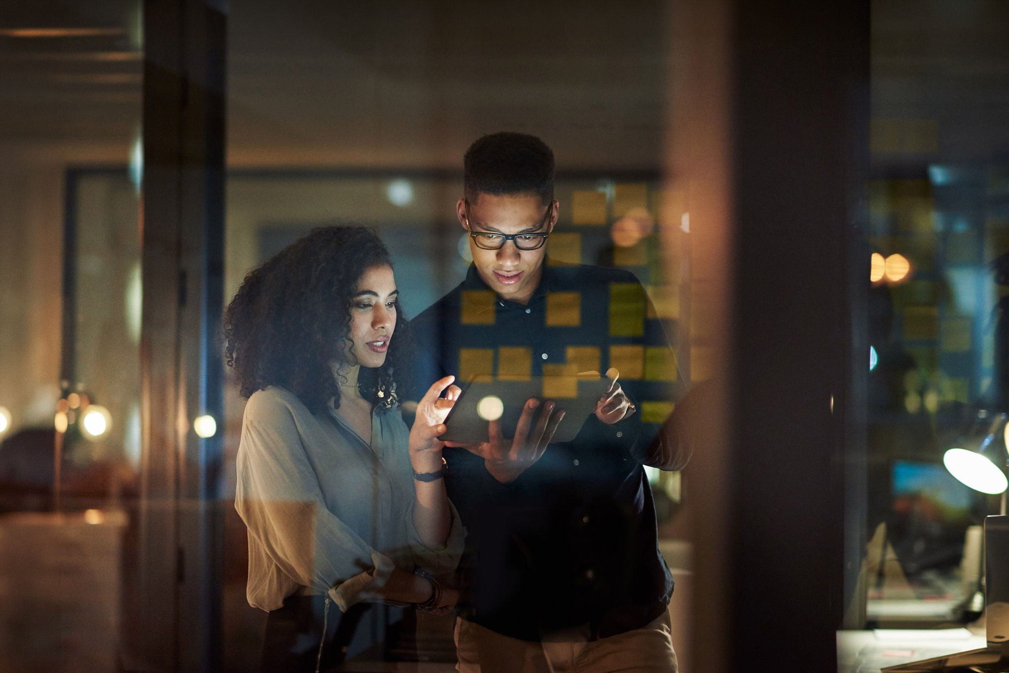 Shot of a young businessman and businesswoman using a digital tablet during a late night at work